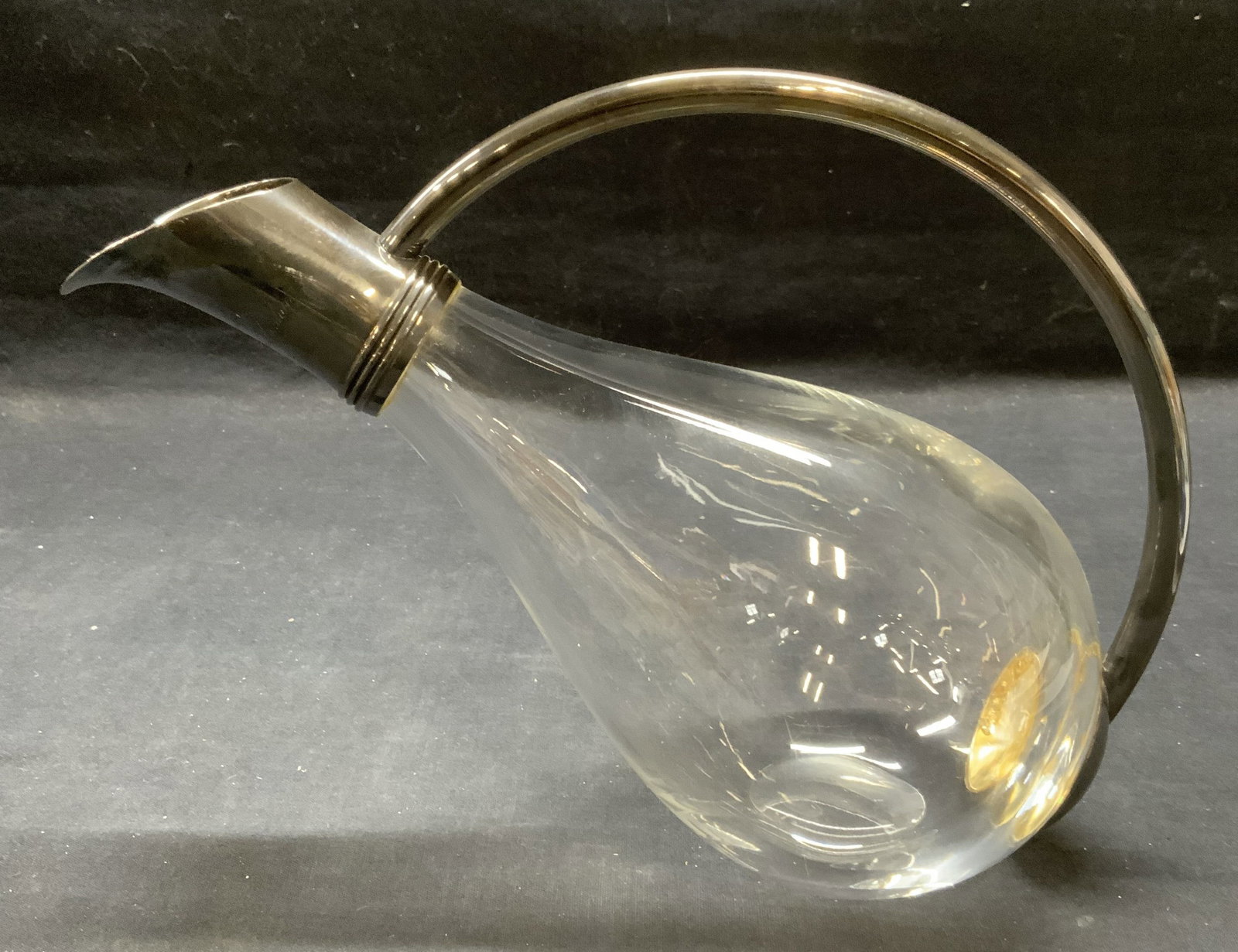 Glass & Silver Plated Wine Decanter: Glass wine decanter with silver plated rim and handle. Engraved on rim, reads Steve Jacobs An American in London 2001-2003. Thick walled glass, piece has weight. Measures approx. 10.5 x 4.5 x 8 inches