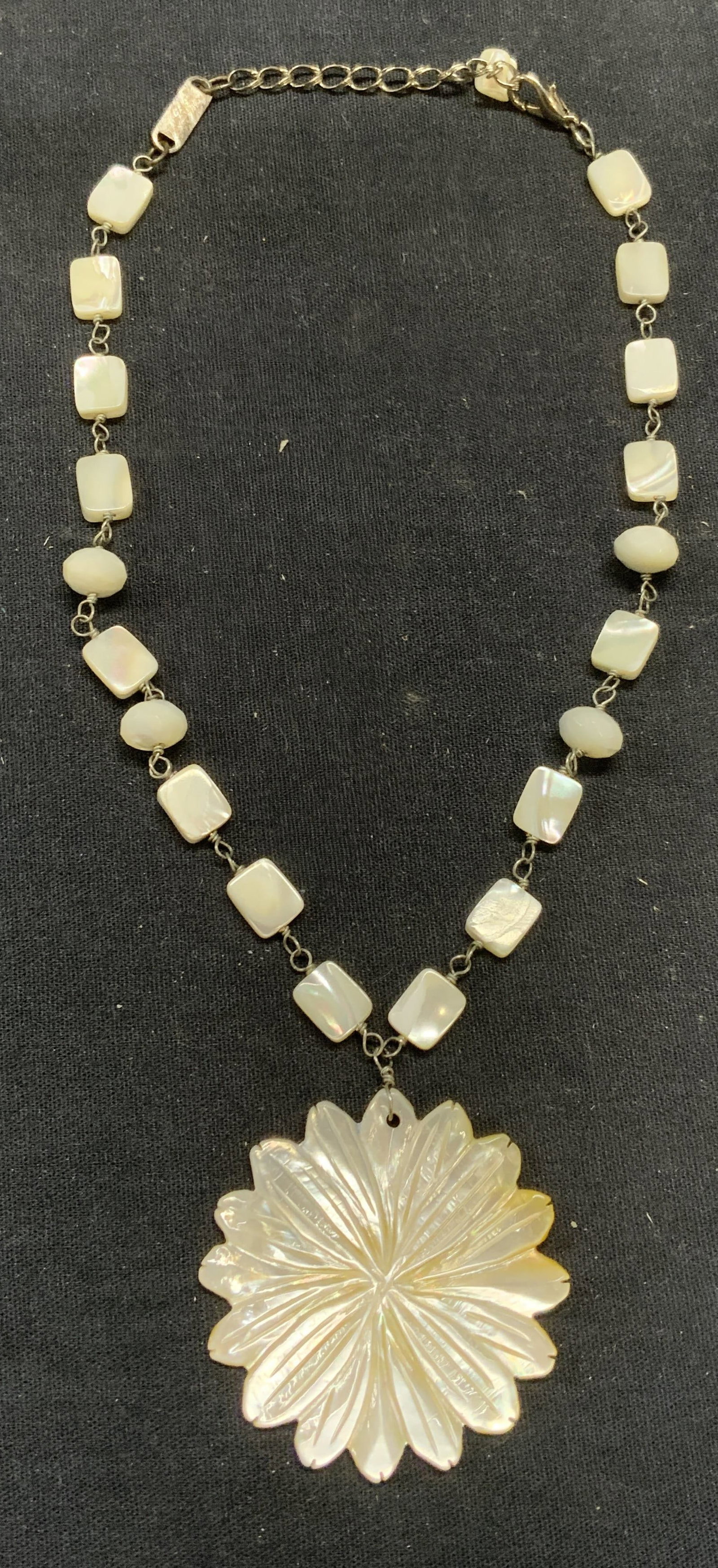 A. V. Max Mother of Pearl Flower Necklace: A. V. Max mother of beaded pendant necklace with flower pendant. Signed on hang tag. Drop length approx. 8 inches. Pendant measures approx. 2 inches wide. Some scratching observed. Estate jewelry, cos