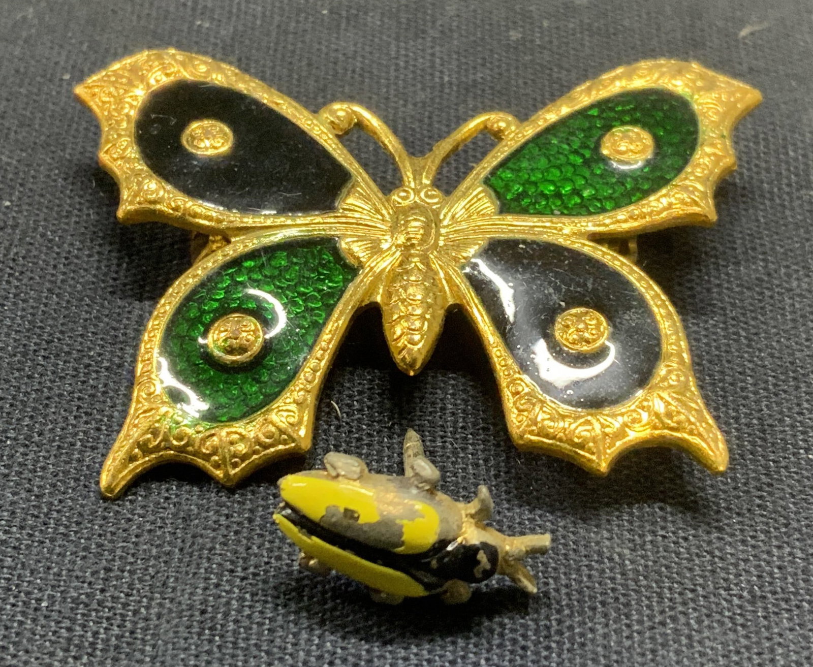 2 Jewelry, Butterfly Brooch & Beetle Pin: Lot of 2 jewelry pieces. Gold tone green enamel decorated butterfly brooch. Hinge pin to underside. Measures approx. 1.75 x 1.25 inches. Enameled Metal beetle pin. Measures approx. 5/8 inches long. So