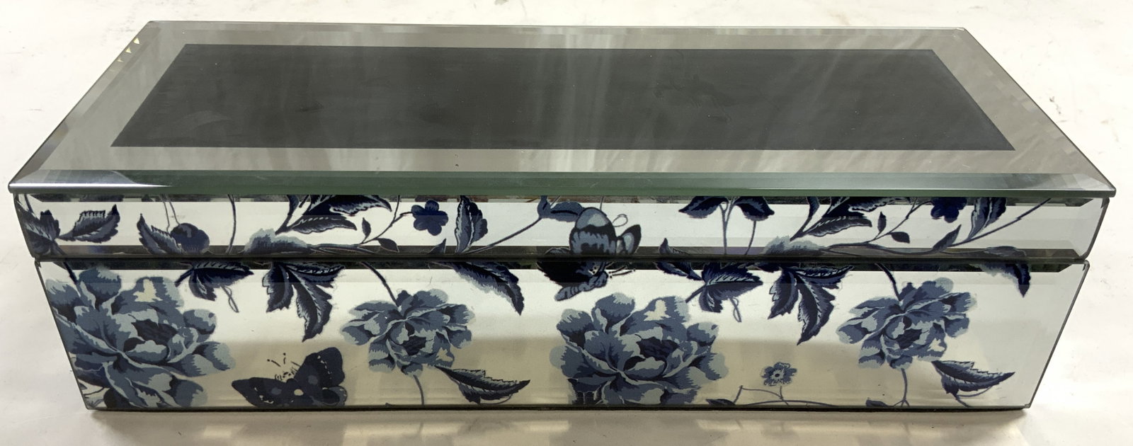 Beveled Mirrored Jewelry Box W Floral Detail: Jewelry Box has mirrored exterior surfaces, each surface beveled. Jewelry box has blue toned floral, leaf & butterfly detail. Interior is black toned crushed velvet. Each measures approximately 11.25 