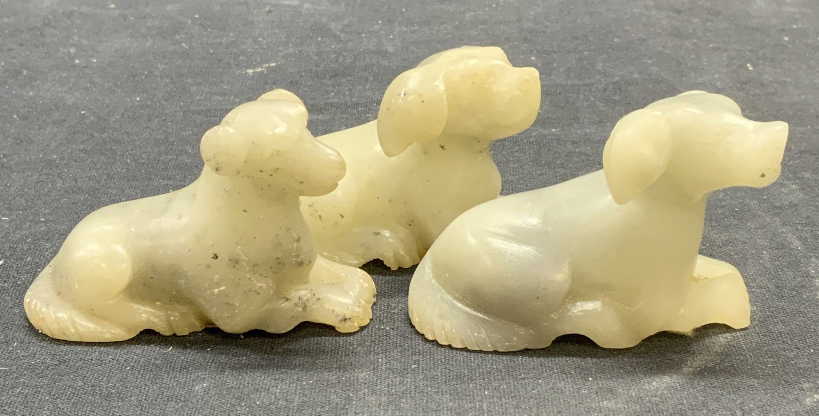 Lot 3 Chinese Stone Dog Figurals: Lot of 3 vintage carved natural stone dog figurines. Made in China. Measure approx. 2.5 x 1 x 1.75 inches each. All pieces have some surface wear including scratching observed. Dog figurine, animal fi
