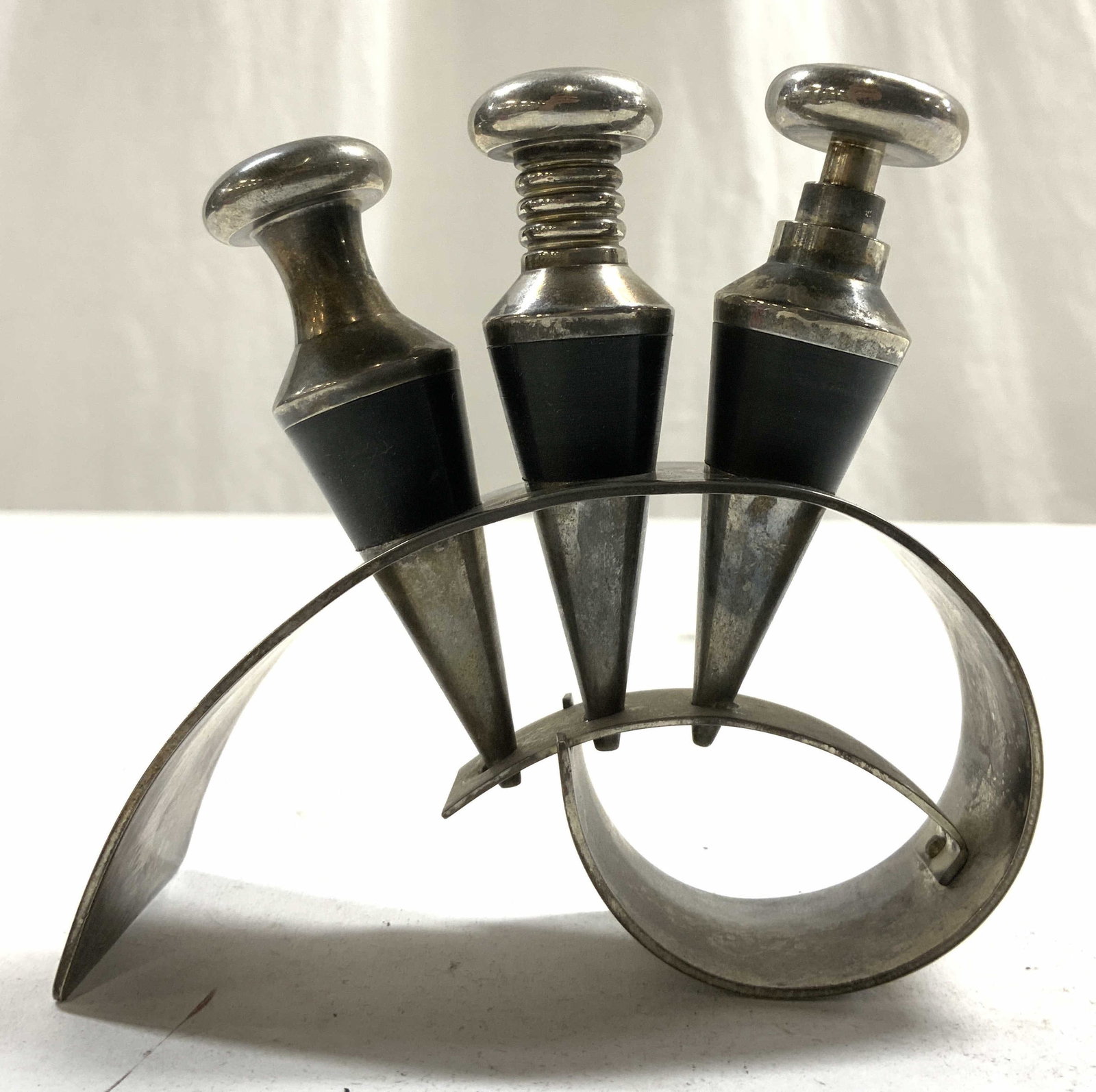 MAZE Silver Pl Postmodern Wine Corks & Holder: Pieces appear to be MAZE (no apparent markings). Lot includes 3 wine corks and 1 wine cork holder. Rack and corks are silver plated. Postmodern wine corks and holder. Cork holder measures approximatel