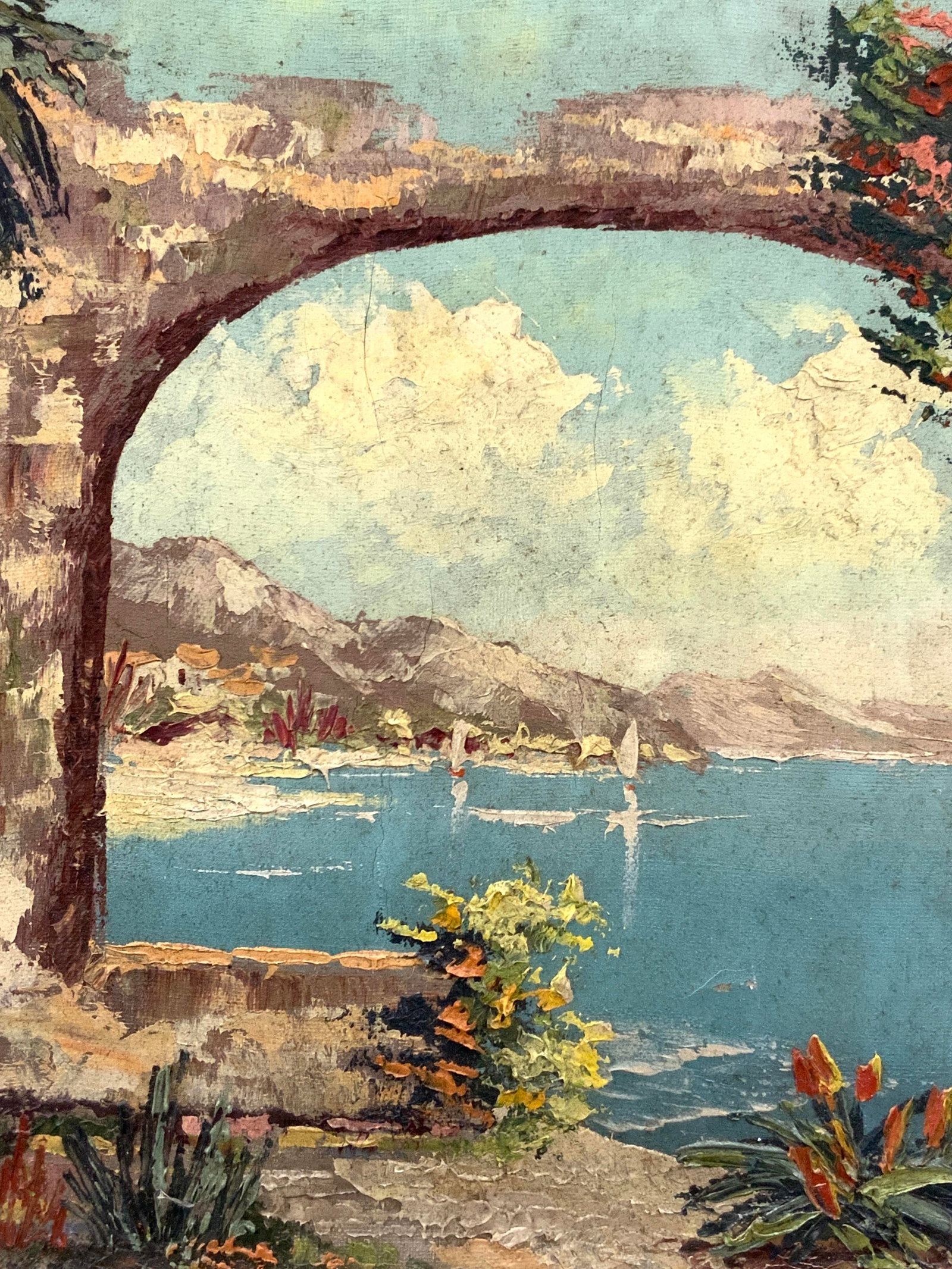 Vtg Landscape Oil Painting On Canvas: Vintage landscape oil painting on canvas depicting a vast ocean from the view of a stone ruin with sail boats on the water and mountains in the distance. Framed in a white wooden frame. Approx 15 x 13