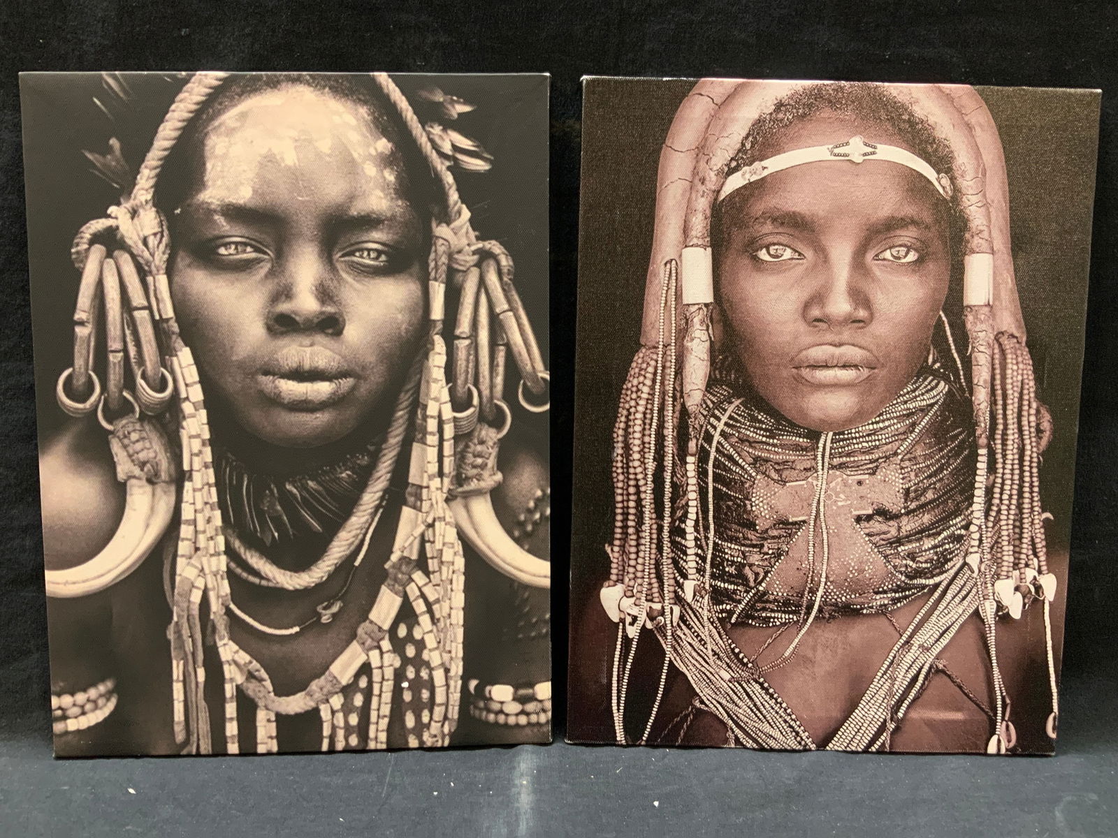 2 African Tribal Women Portrait Lithographs: Lot of 2 lithographs depicting portrait photographs of African tribal women, adorn with head dresses made of clay, horns and beads in black and white and sepia tones. No frames. Approx 16 x 11.5 inche