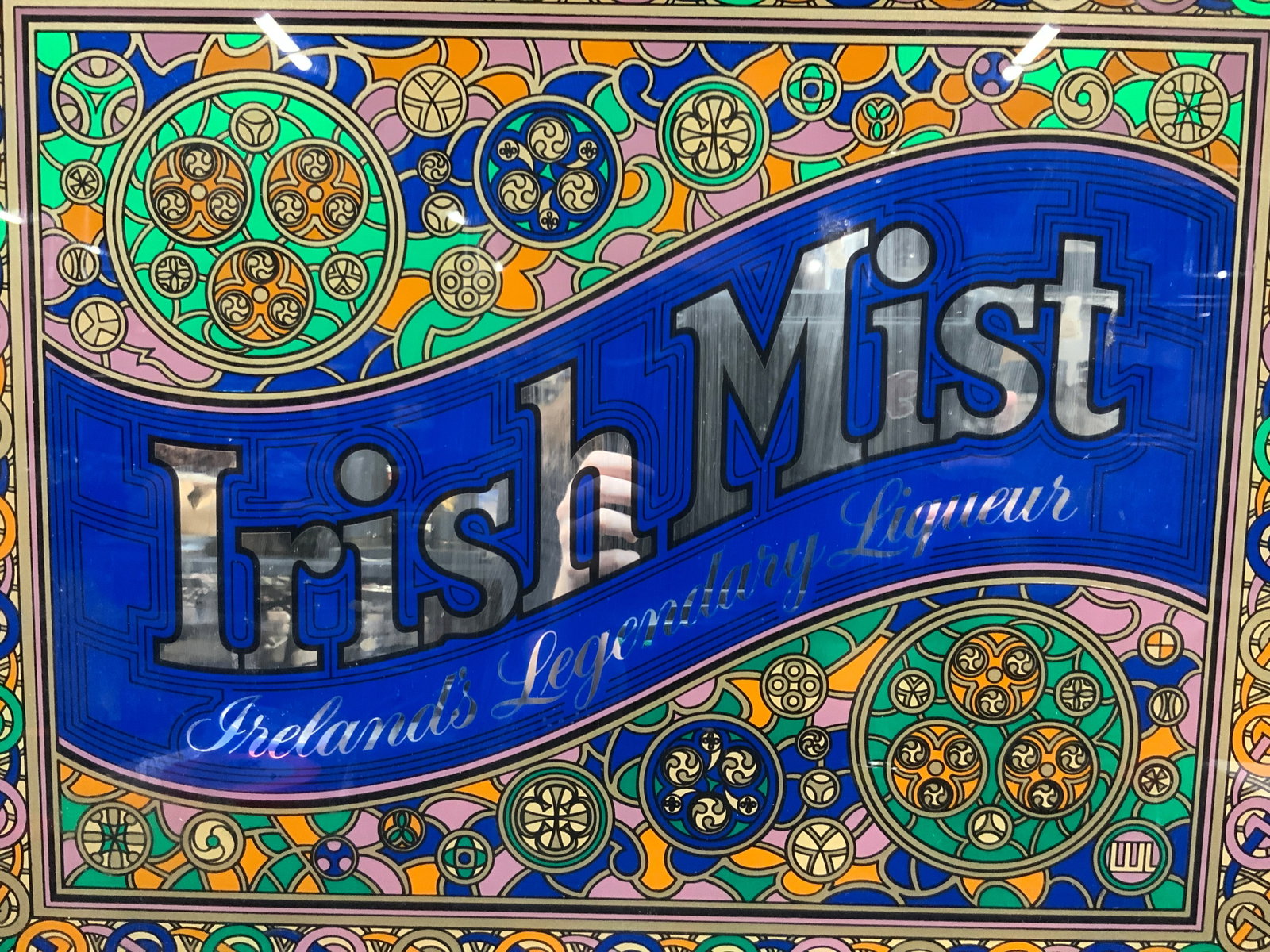 Vintage Irish Mist Glass Wall advert: Vintage glass advert reading Irish mist, Irelands, legendary liqueur. With mosaic style color boxing designs in green pink and orange. Framed in a brown wooden frame. Approx 20 x 24 inches window meas