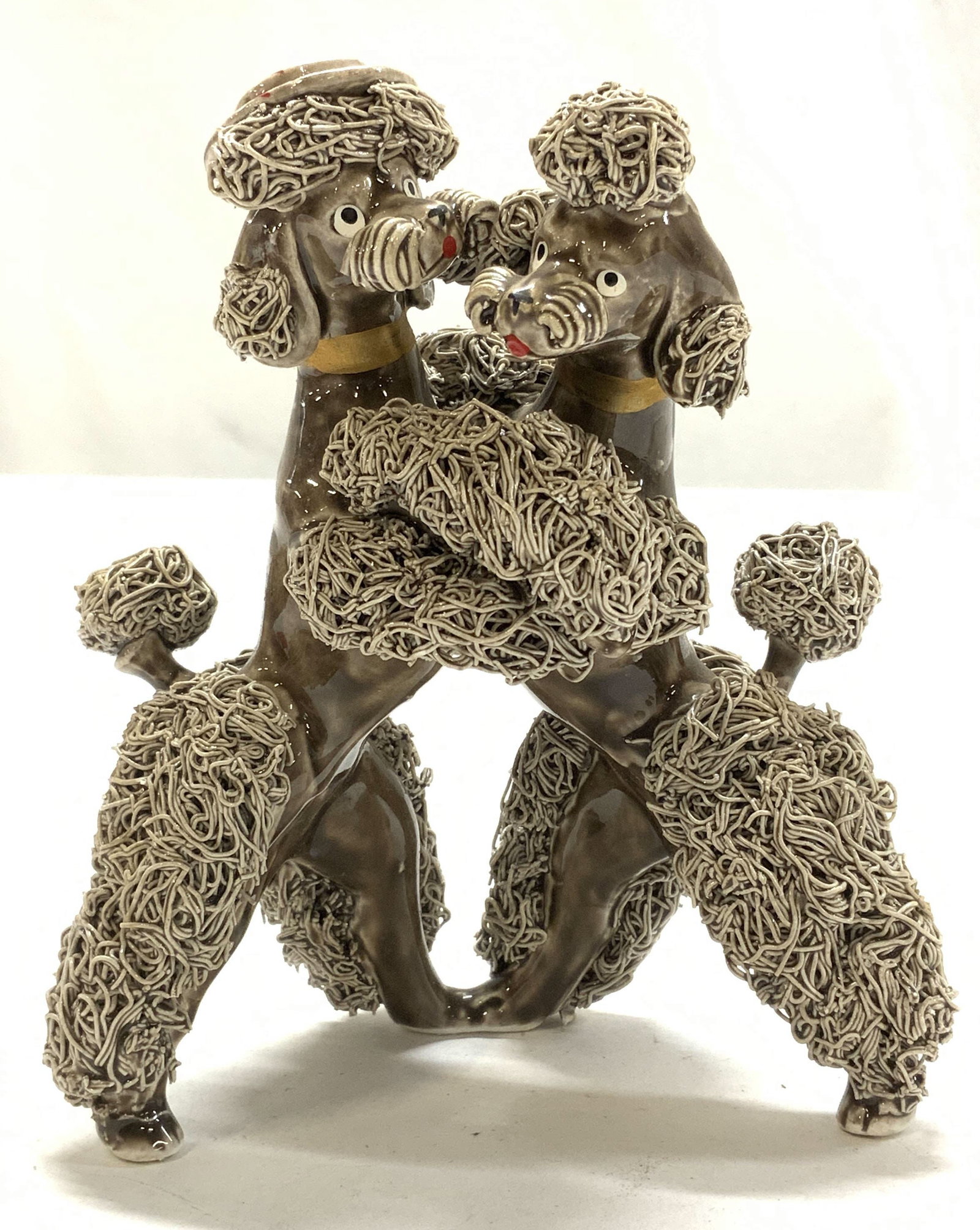 Dancing Porcelain Pom Pom Poodles , Hand Crafted: Artisanal ceramic poodles in upright position, hunting and dancing. Layered Spaghetti strips as the decorated pop pom and poodle cuts. Painted eyes and tongue mocha glazed coloring. Measures 5.25 in. 