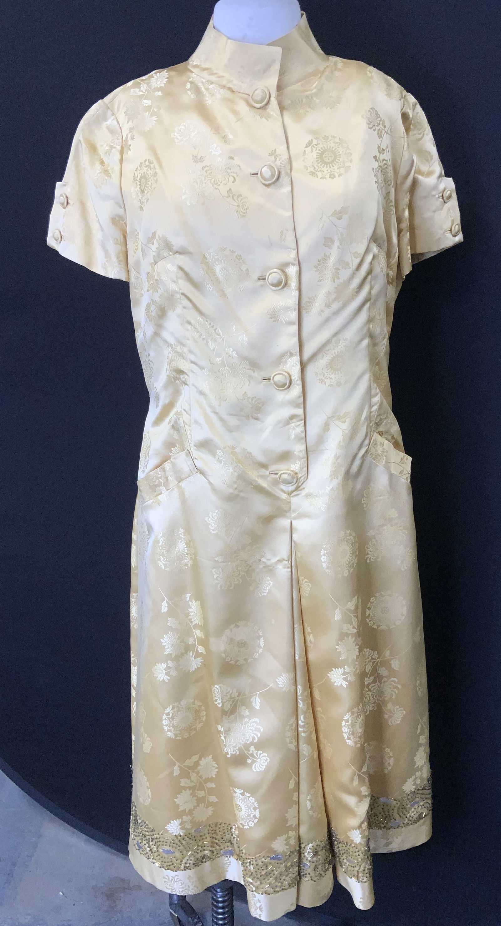 Gold Silk Vintage Asian Dress w Beading: Gold silk Asian dress with high collar and silk fabric buttons. Has hand pockets and beaded lower hem . Shirt sleeves with buttons. Tonal Asian floral medallions , chrysanthemum and other Asian floral