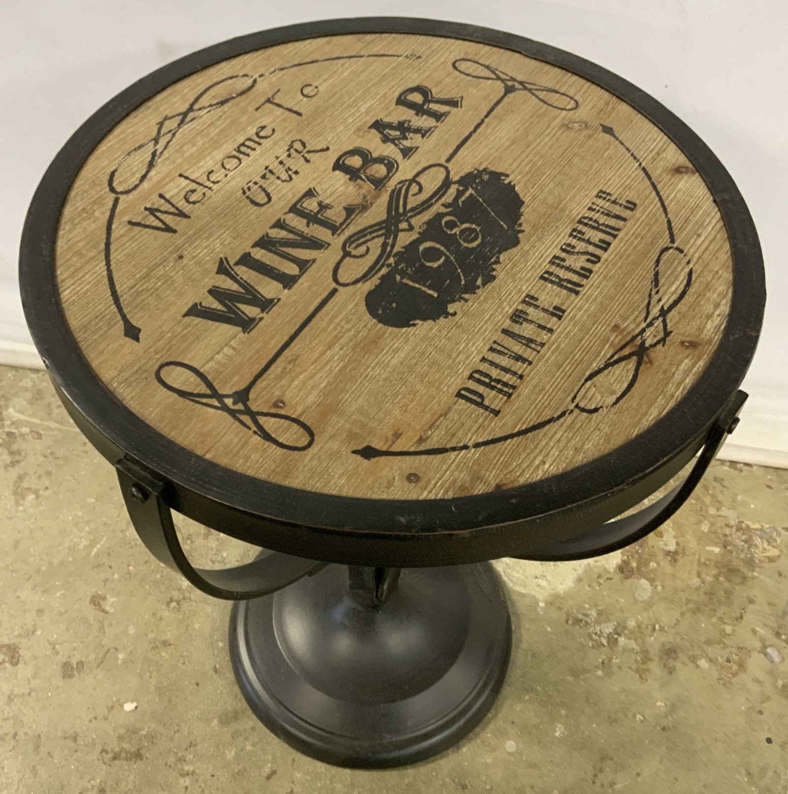 PIER 1 Wooden Wine Bar Sign Motif Side Table: A round top side table crafted from metal and wood. Tabletop features a wine bar sign which reads WELCOME TO OUR WINE BAR, 1987, PRIVATE RESERVE. Measures approx. 24H x 18W in. Underside sticker reads