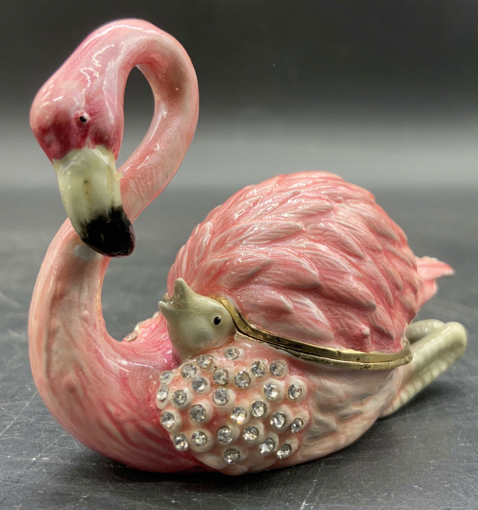 Bejeweled Enameled Pink Flamingo Trinket Box, Lid: A enameled and bejeweled trinket / pill box. Flamingo form and primarily pink in color. A flamingo chick can be seen peeking out from beneath the mother. Magnetic lid. Measures approx. 2H x 2.5W in. M