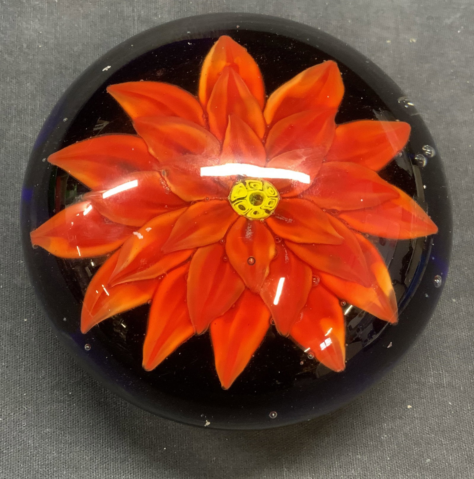Hand Blown Art Glass Flower Paperweight: Hand blown art glass paperweight with flower motif in red and blue. Measures approx. 4 inches wide. Some surface wear including scratching observed. Paperweight, flower paperweight, art glass paperwei