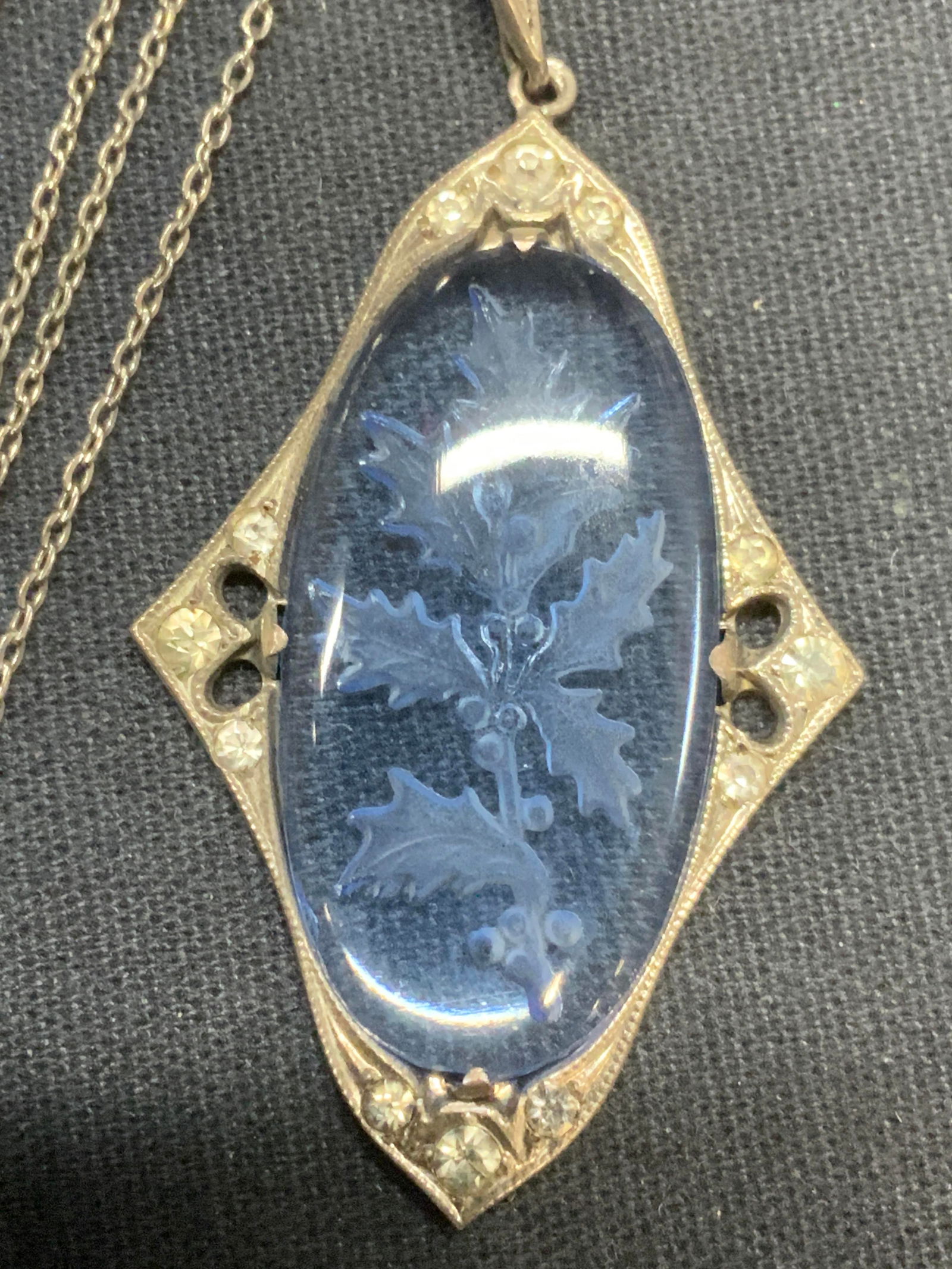 Sterling Silver Glass Intaglio Pendant Necklace: Vintage sterling silver necklace and pendant. Blue glass intaglio pendant with holly branch motif and crystal decoration. Marked sterling in pendant and necklace clasp. Drop length approx. 10.25 inche