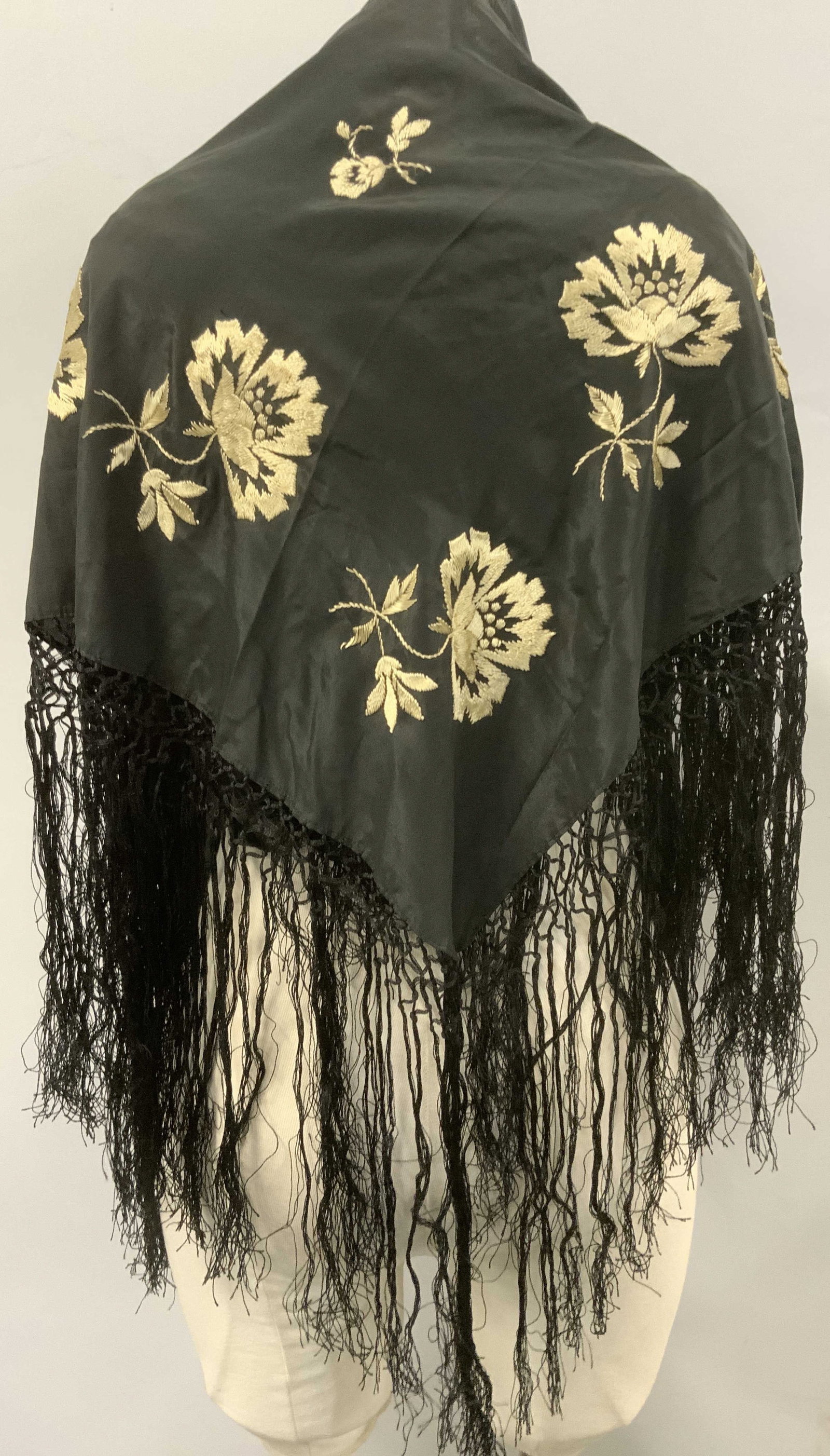 Black silk embroidered Flamenco Shawl: 34 x 35 in embroidered silk tassel shawl. Tassels measure an extra 11.5 in. Long. Black silk with hand embroidered flowers in tan silk thread. This garment is fragile with moderate rips in the silk at
