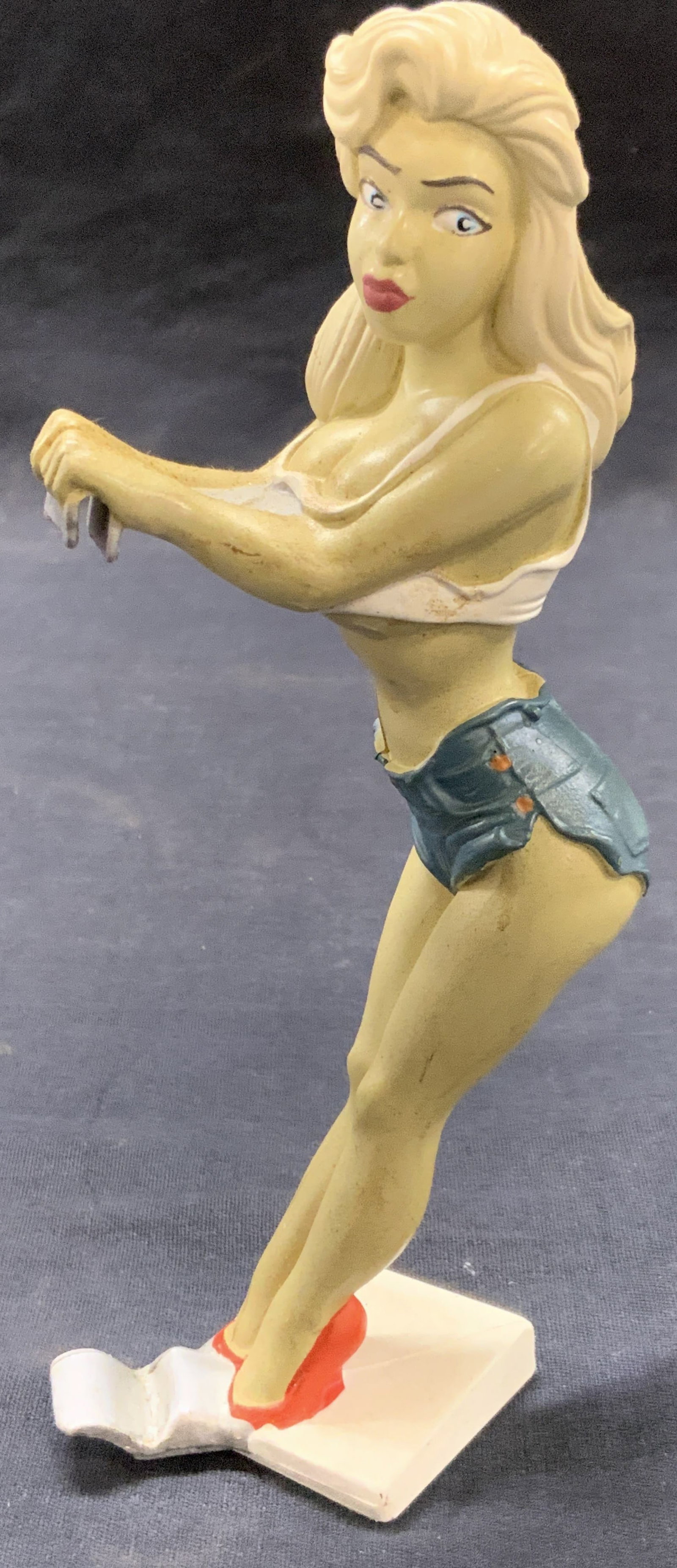 Vtg Bottoms Up R Demars Ganz Pin Up Can Holder: Vintage pin up girl Bottoms up R demars Ganz soda can holder depicting a blonde woman in short shots and cropped top with notches on the base of the figure and hands of the figure to hold a beer can. 