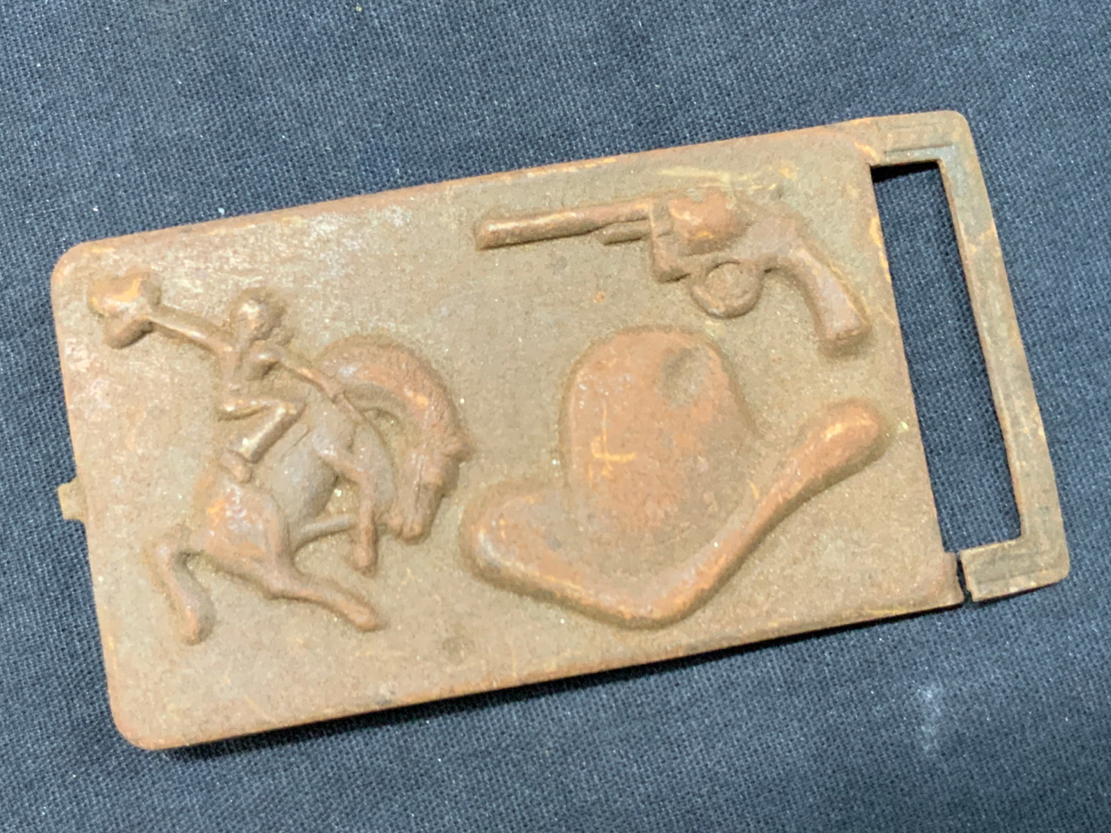 Vtg Embossed Metal Cow Boy Belt Buckle: Vintage metal crafted belt buckle, possibly made of aluminum. Embossed with images of a cow boy hat, a revolver gun and a man on the back of a bucking horse. Approx 2 x 3.75 inches. Evident rusting to
