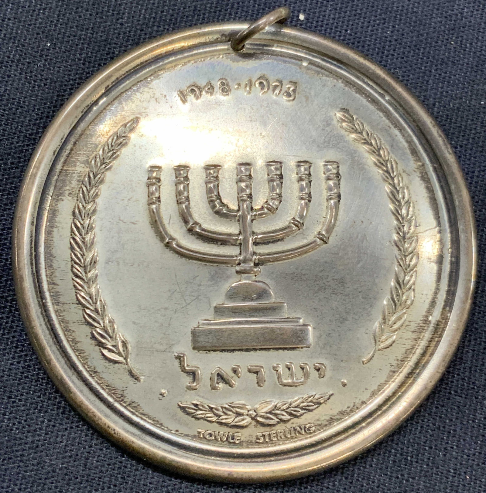 Towle Sterling Silver 25Yr Israeli State Pendant: Towle sterling silver pendant of the 25th anniversary of The State of Israel. Depicting a Menorah on one side and the Star of David on the other side. And Israel written in Hebrew 1948-1973. Approx 2 