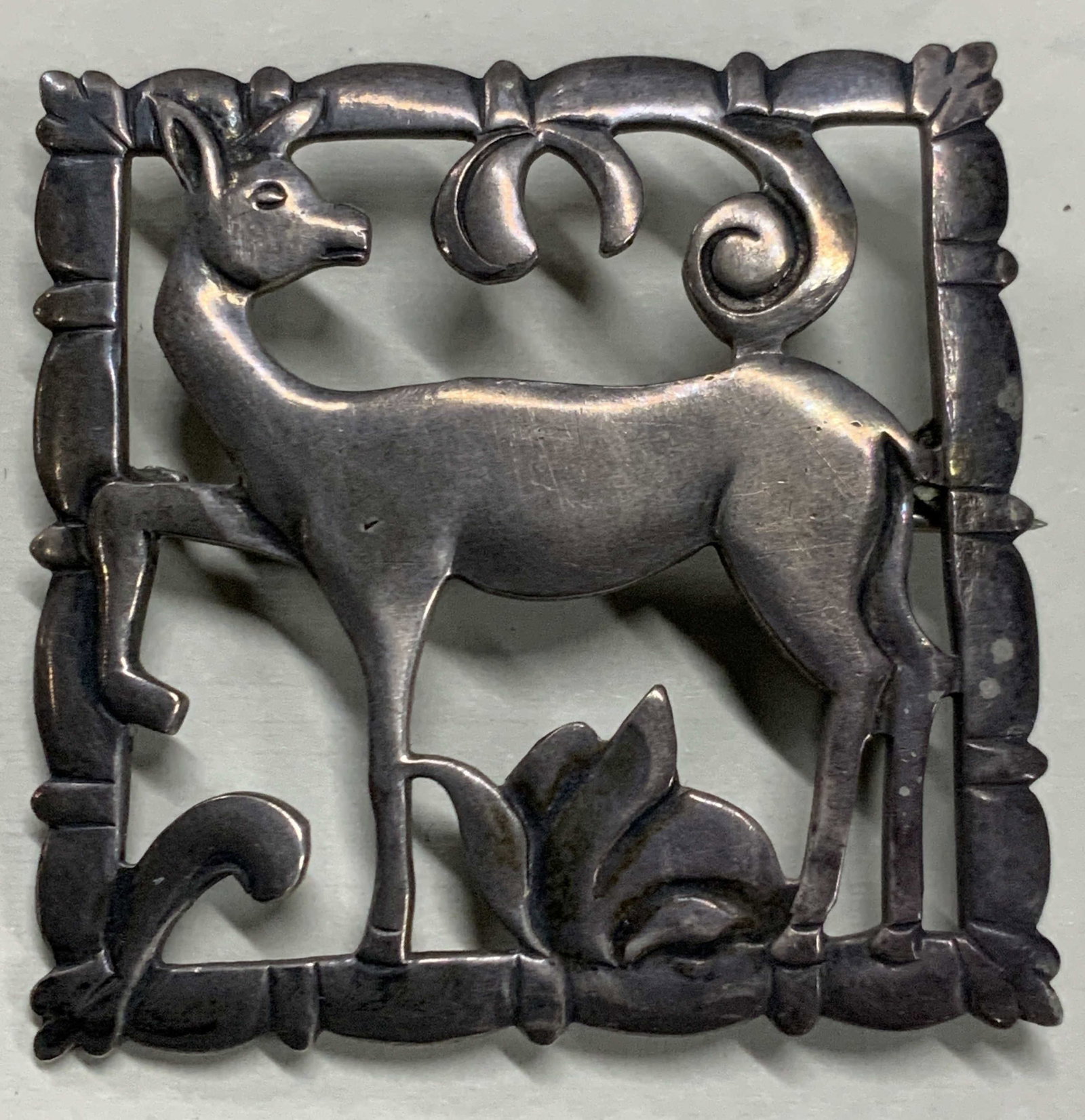 Sterling Silver Art Nouveau Deer Brooch: Sterling silver stamped art nouveau brooch with a center deer motif with floral motif. Approx 1.5 x 1.5 inches. Moderate discoloration due to age and use. Sterling silver brooch, sterling brooch, ster