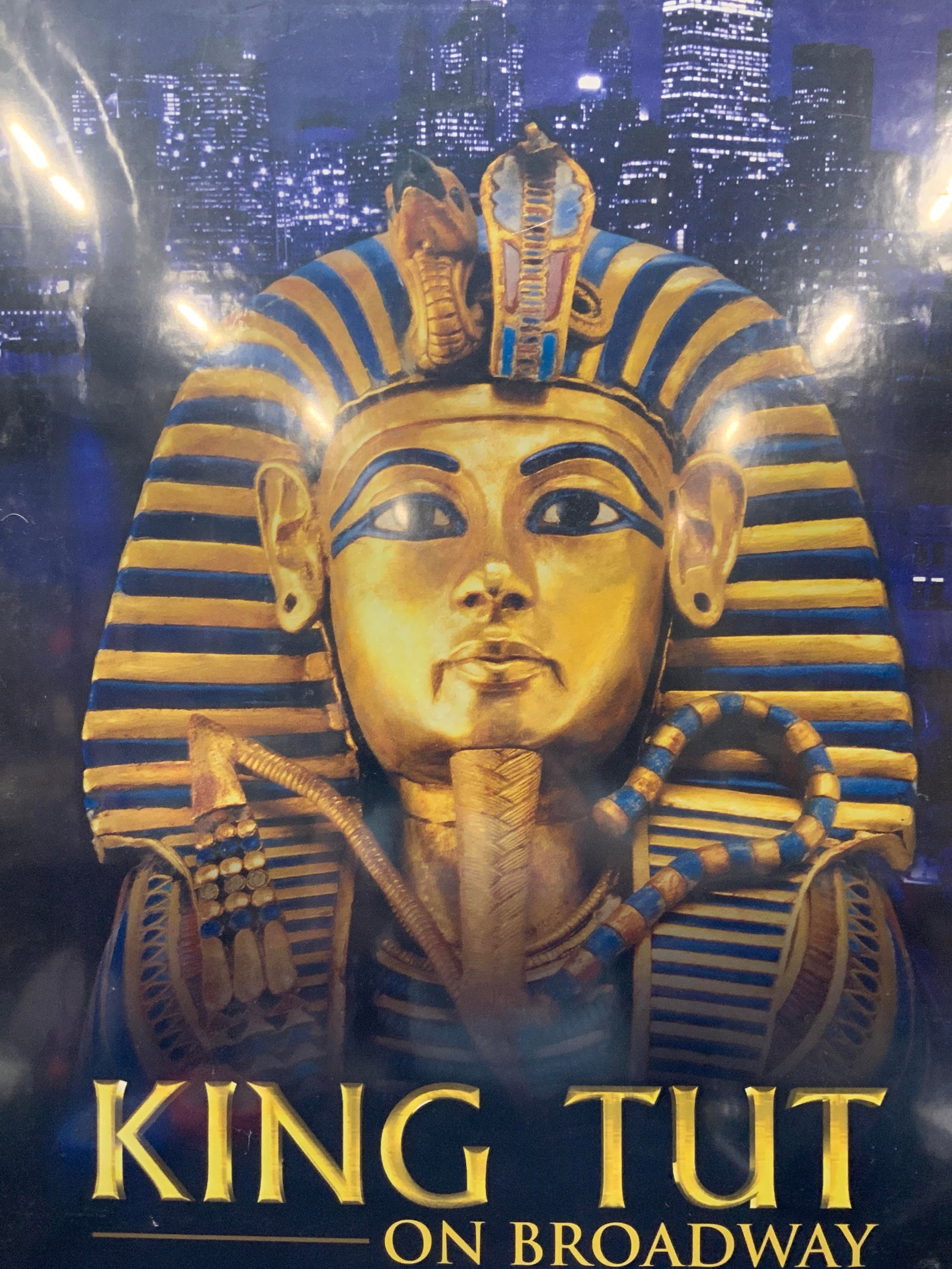 King Tut On Broadway Lithograph Advert: Lithograph advert for King Tut on Broadway with an image of a sarcophagus and New York City in the distance. Framed in a black plastic frame, approx 3ft x 2ft and window measures 25.75 x 23.75 inches 