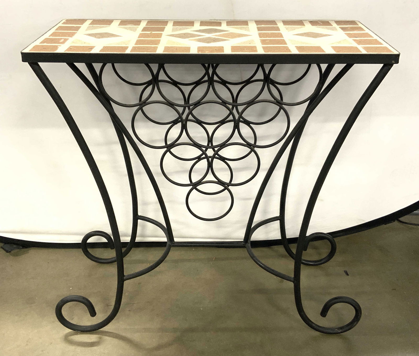 Stone Top Iron Wine Rack Table W Curled Feet: Table has stone mosaic top with multi toned geometric detail. Piece has black toned iron frame. Wine rack has 10 bottle areas. Piece has 4 c curled feet. Tabletop has rectangular shaped top. Piece mea