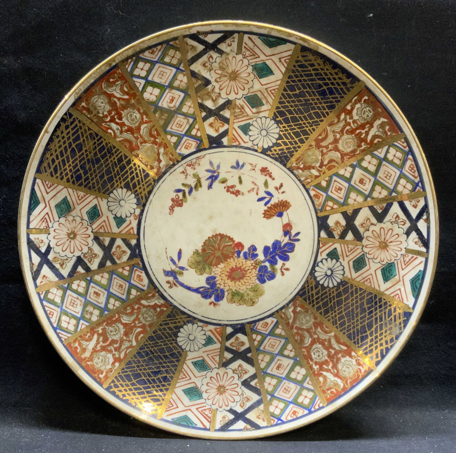 Antique Japanese Imari Gilt Porcelain Plate: Antique Japanese porcelain plate. Hand painted imari pattern with gilt decoration. Hues of blue and red with floral motif. Measures approx. 12.25 inches wide. Surface wear including scratching and los