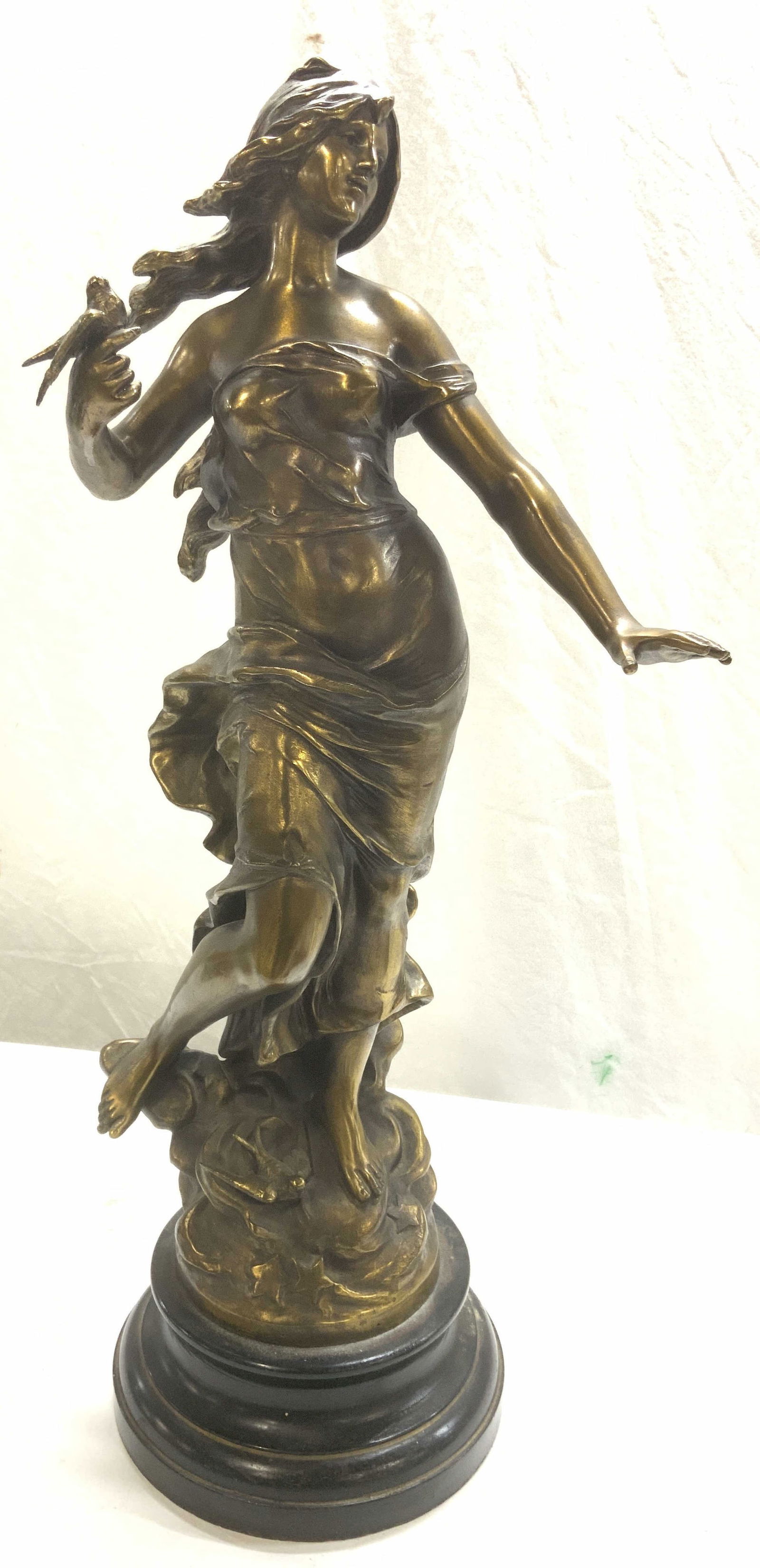 Auguste Moreau Antq Gilt Metal Statue, France: Art nouveau statue of a young woman holding a bird on her hand, wearing airy an robe with flowing locks. Gilt Metal in a painted black metal base. Has a Stamp Fabricacion Francais Made in France & Sig