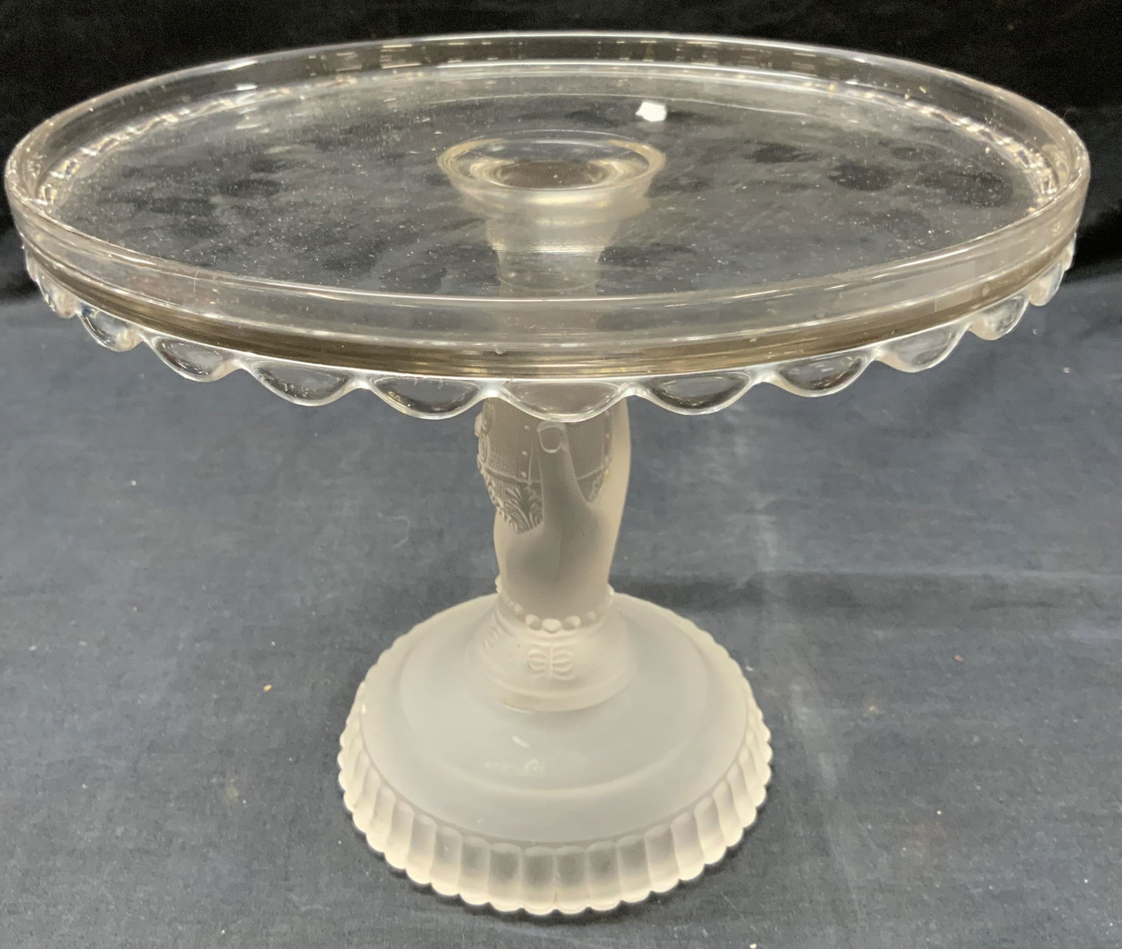 Vtg Hand Motif Glass Cake Pedestal: Vintage glass made cake dish pedestal with the top made of clear glass with scalloped edges and the neck and base made of frosted glass with a hand as the neck made to resemble it holding up the dish.