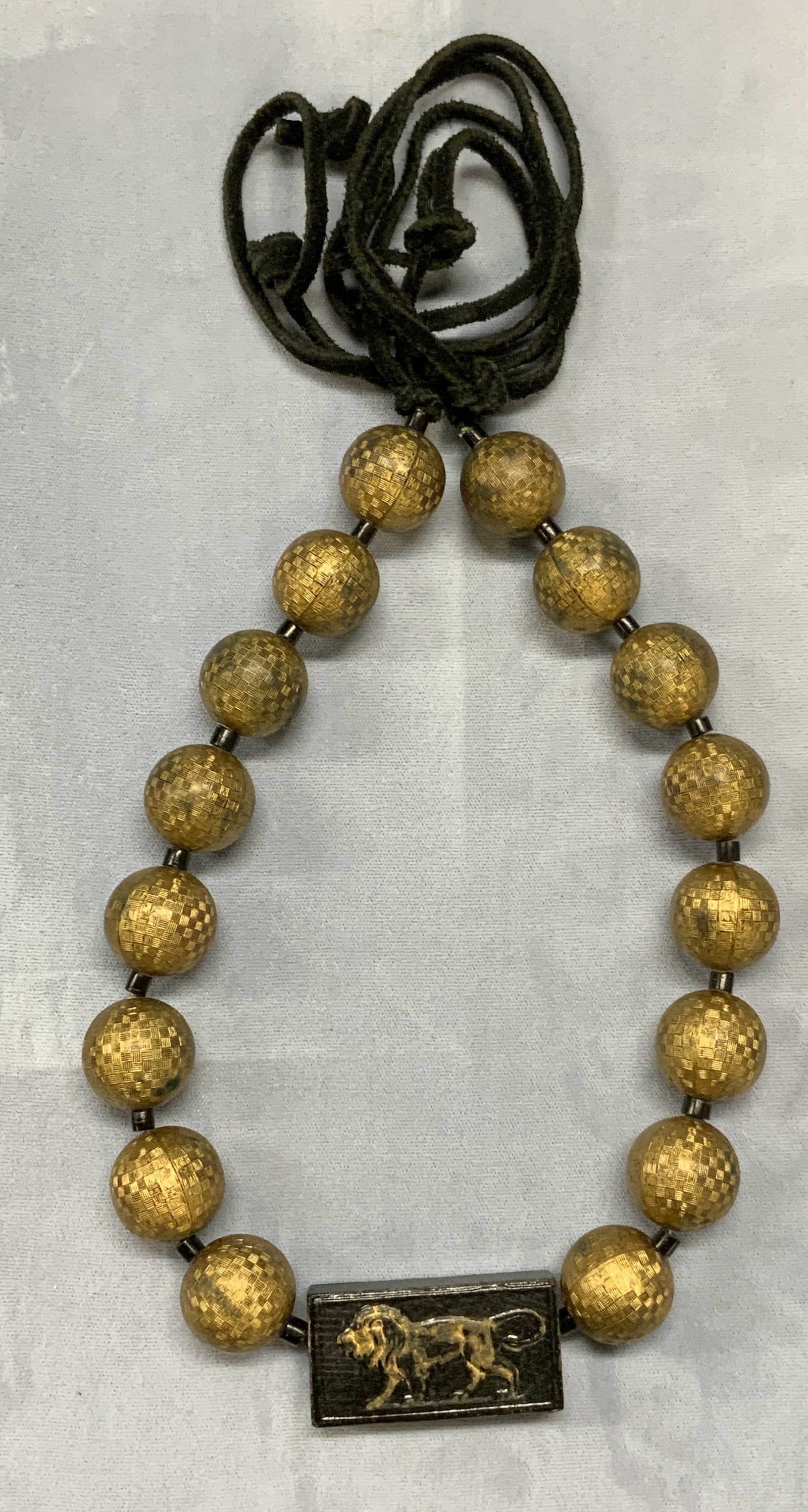 Vintage Gold Tone Lion Pendant Necklace: Vintage gold tone beaded necklace on black cord with lion motif pendant. Drop length approx. 15 inches. Some surface wear including scratching observed. Estate jewelry, costume jewelry, cocktail jewel
