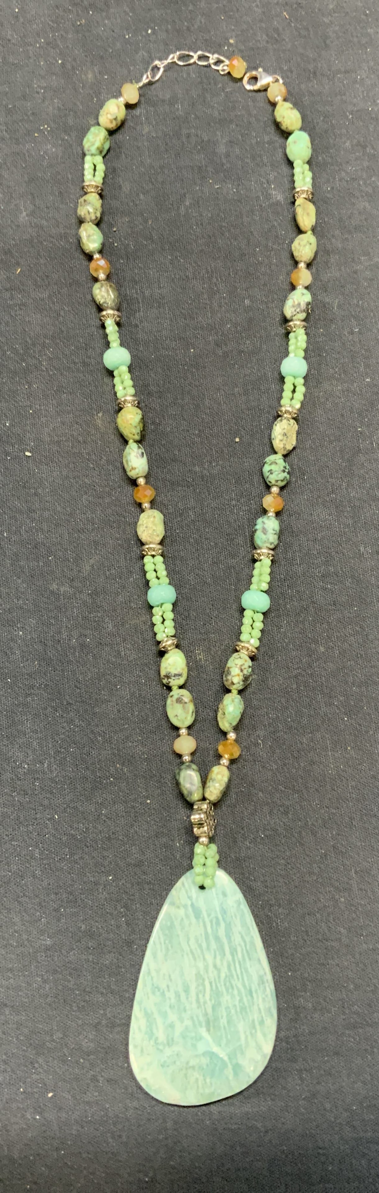 Blue & Green Toned Gemstone Pendant Necklace: Blue and green toned beaded gemstone and crystal necklace with blue stone pendant. Sterling silver clasp marked 925. Drop length approx. 10 inches. Some surface wear including scratching observed. Est