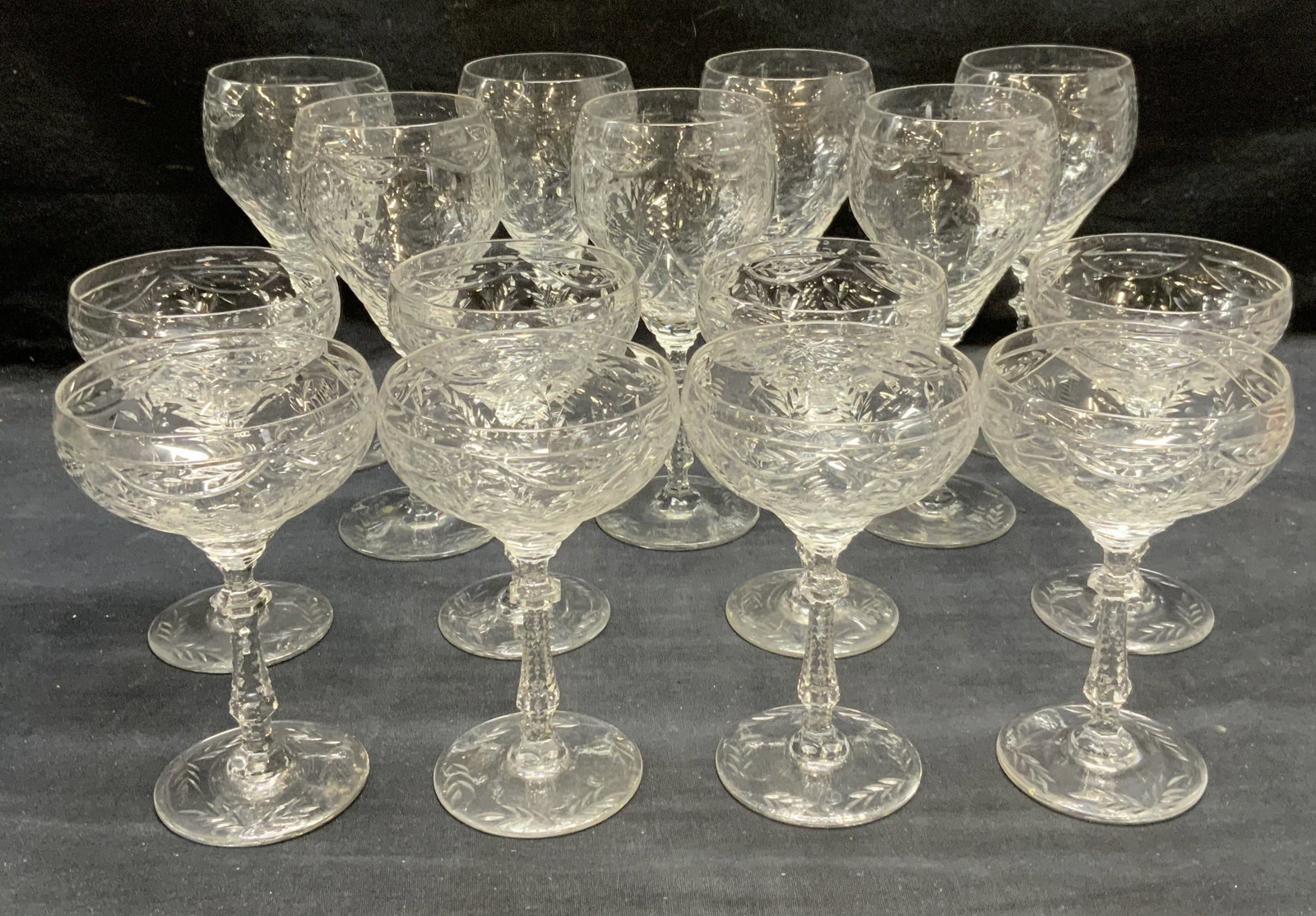 Set 15 Crystal Wine Glasses: Set of 15 crystal wine glasses with floral scroll pattern. Larger glasses measure approx. 3.5 x 8 inches. Smaller glasses measure approx. 4 x 6 inches. All pieces have some surface wear including scra