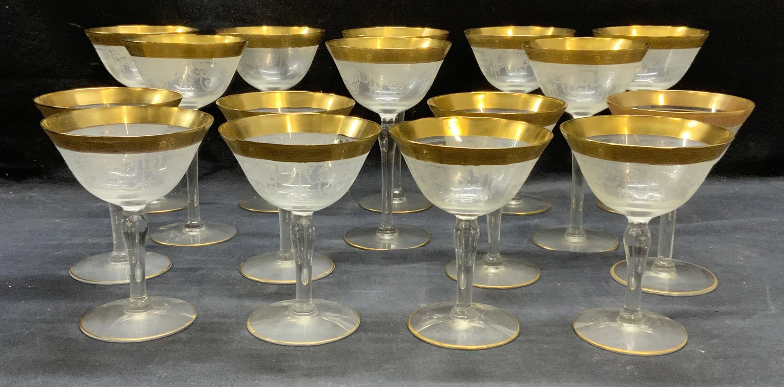 Set 16 Gilt Etched Wine Glasses: Set of 16 wine glasses with gilt rims and etched floral scroll patterns. Larger glasses measure approx. 3.75 x 6.5 inches. Smaller glasses measure approx. 4 x 5 inches. All pieces have some surface we