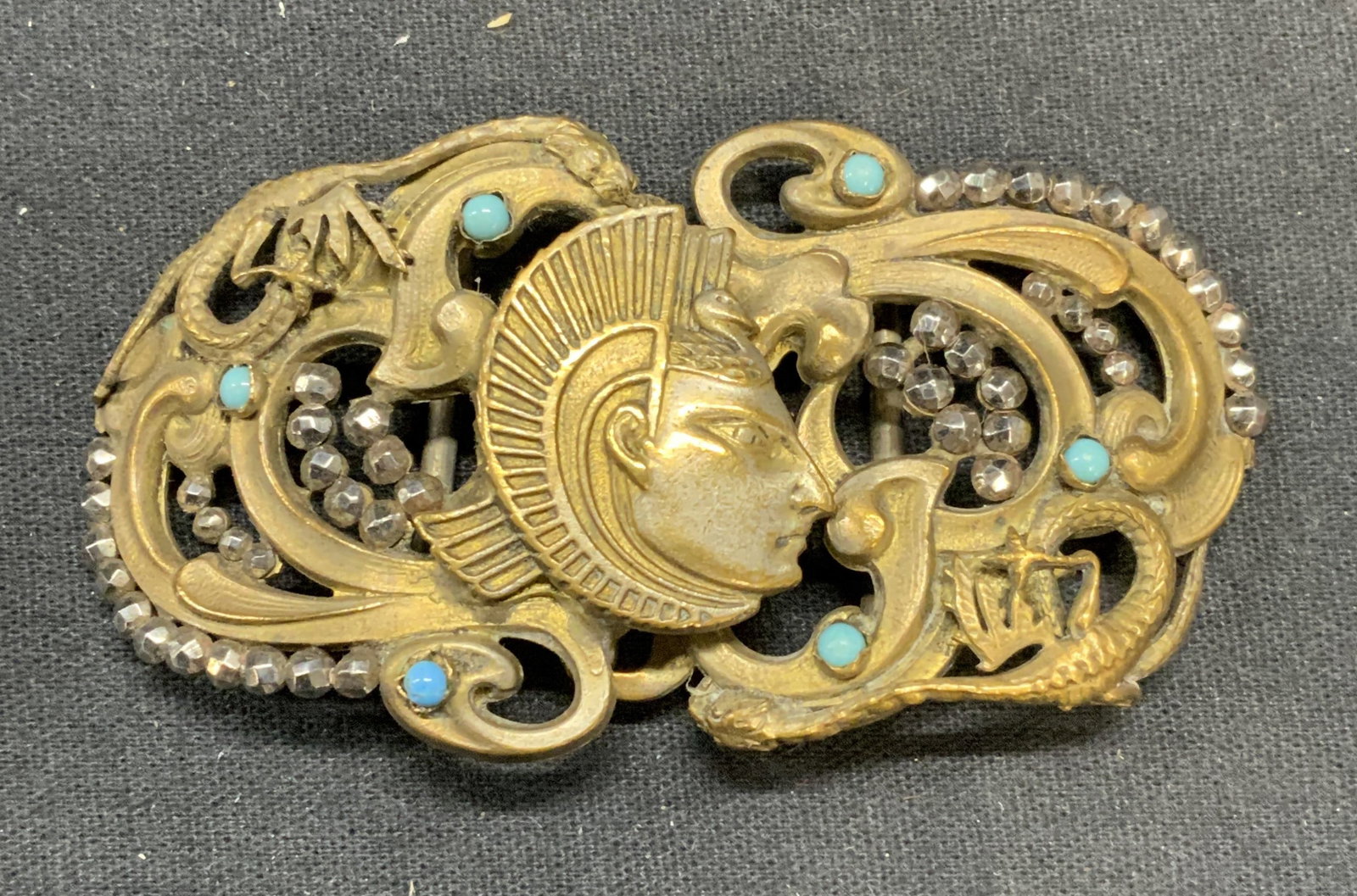Vintage Gold Tone Crystal Egyptian Belt Buckle: Vintage gold tone Egyptian revival style belt buckle with embossed figural and scroll motif. Metallic crystal and turquoise style cabochon decoration. Measures approx. 3 x 1.75 inches total dimensions