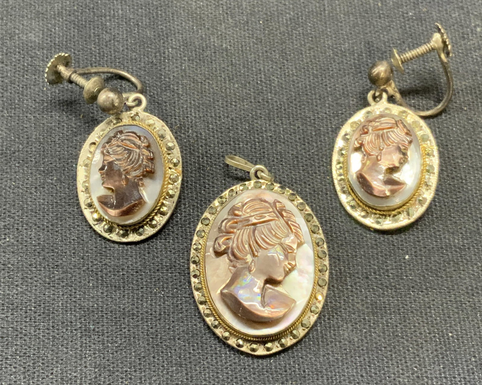 Lot 2 800 Silver Cameo Pendant & Earrings: Matching vintage 800 silver cameo pendant and earrings. Mother of pearl and marcasite decoration. Carved cameo motif. Marked 800 on pendant. Pendant measures approx. 1 x .75 inches. Earrings measure a