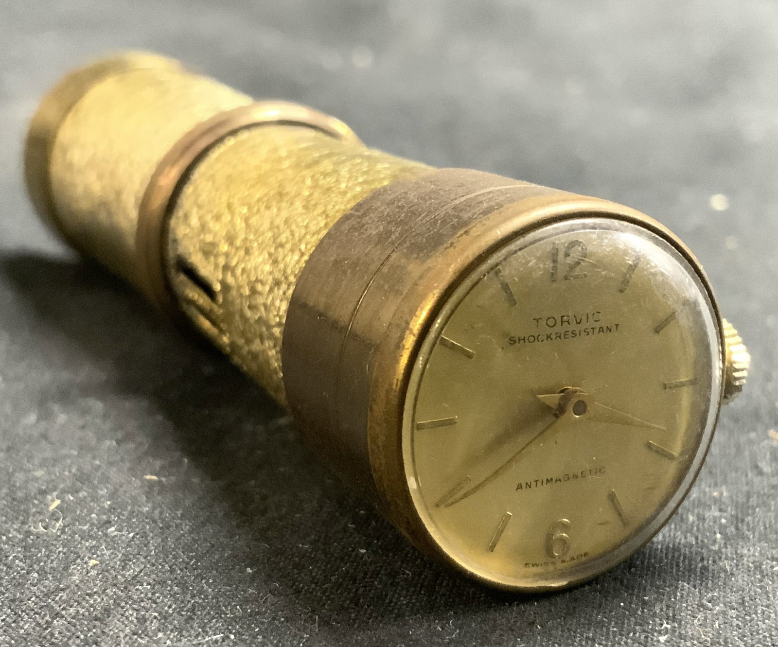 TORVIC Swiss Vintage Watch Lighter: Clock face reads TORVIC ANTIMAGNETIC SWISS MADE. Watch lighter combination is gold toned & metal. Backside has floral form detail with rhinestones. Piece measures approximately 3.25 inches long .75 in
