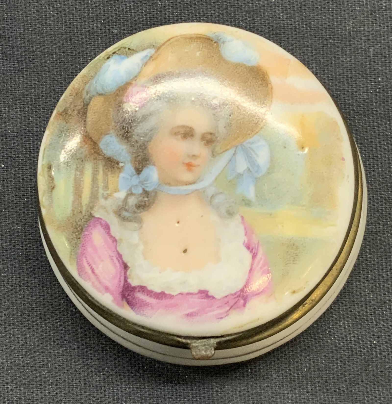 Vintage Figural Porcelain Trinket Box, Germany: Vintage, possibly antique, hand painted gilt porcelain trinket box with figural motif. Marked Germany to underside. Measures approx. 2 x 1 inches. Some surface wear including scratching observed. Trin