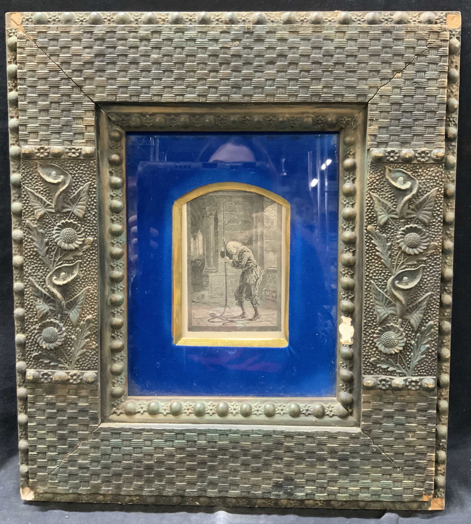 EHG FTM Vintage Book Illustration Engraving: Vintage Engraving of a man sulking while holding the rope to a clock tower. Marked EHG FTM Framed in an ornately crafted wooden frame in black and blue tones with wicker textures and raised floral mot
