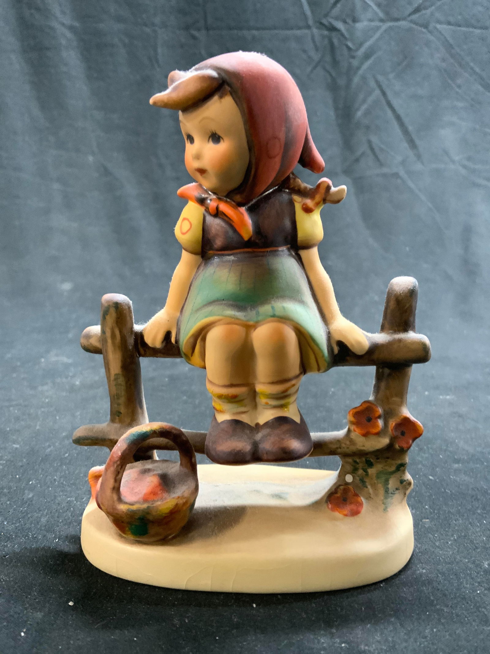 GOEBEL HUMMEL Just Resting Porc Figural Germany: Base inscribed MI HUMMEL Underside marked W GOEBEL WEST GERMANY. Tag reads JUST RESTING. Piece depicts a female child figure sitting on a wooden fence with basket at feet. Figure is vintage and porcel