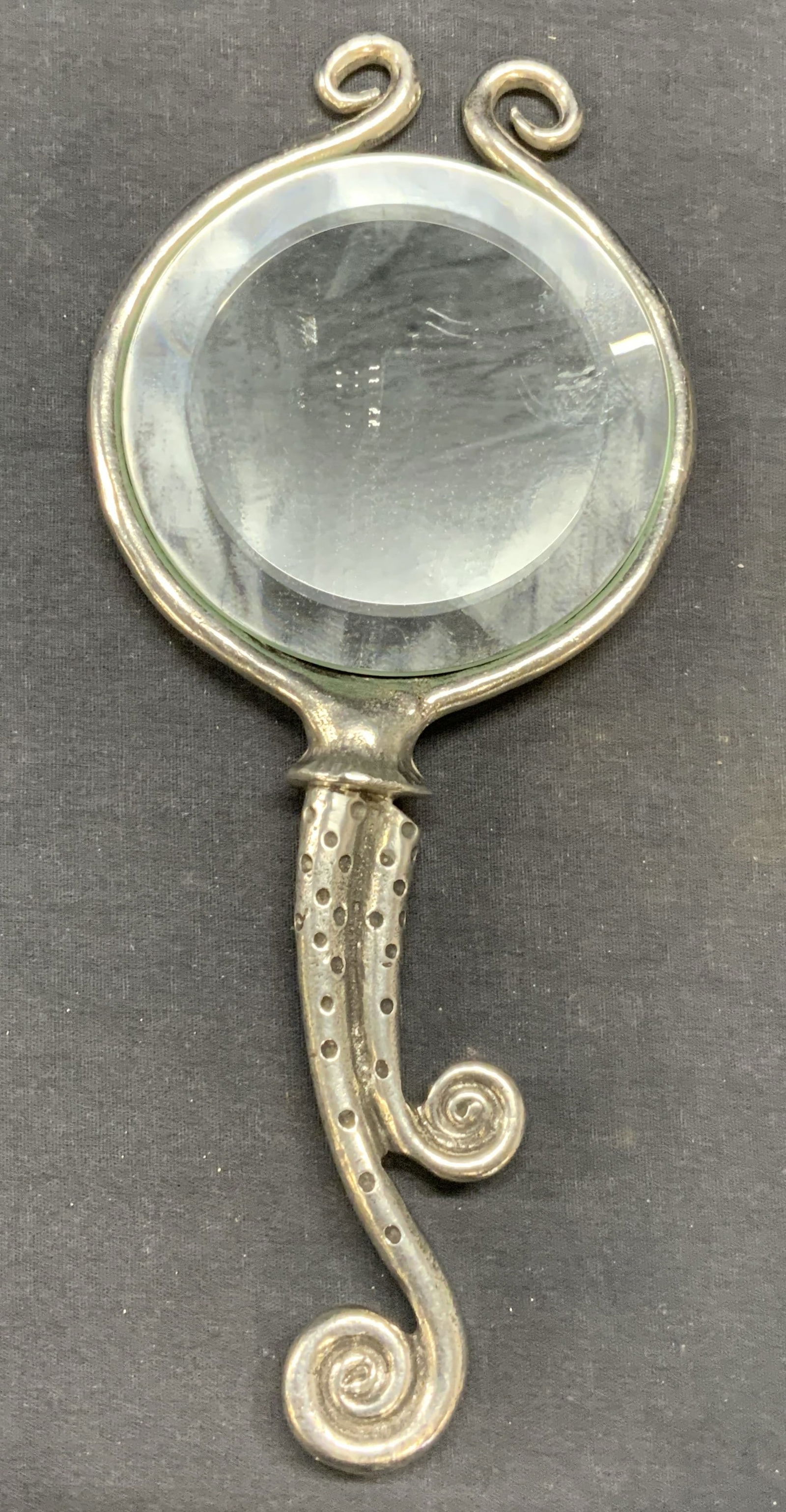 Vintage Whimsical Silver Tone Hand Mirror: Vintage whimsical silver tone hand mirror with beveled glass. Measures approx. 10.25 x 4.5 inches. Piece has weight. Some surface wear including scratching observed. Mirror, hand mirror, whimsical mir