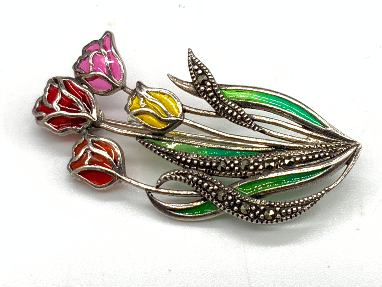 STERLING SILVER 925 Multicolored Floral Brooch: A sterling silver brooch decorated with faceted marcasite and multicolored resinous fill to give a stained glass effect. Floral bouquet form. Reverse possesses metal pin closure and is marked 925. Mea