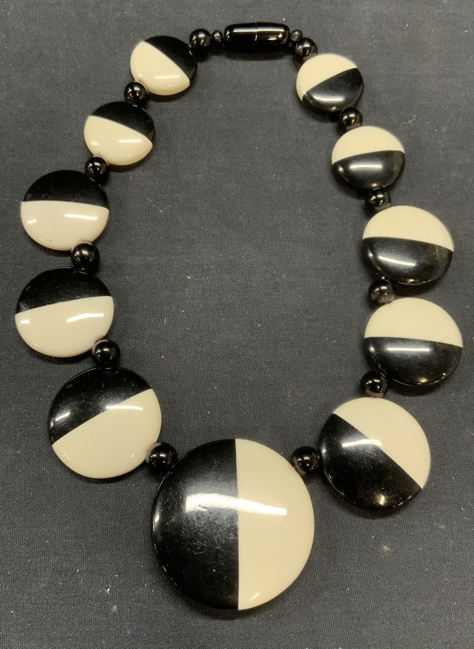 Vintage Black & White Beaded Necklace: Vintage black and white disc beaded necklace. Beads feel like lucite. Drop length approx. 7 inches. Largest bead approx. 2.25 inches diameter. Some scratching observed. Estate jewelry, costume jewelry