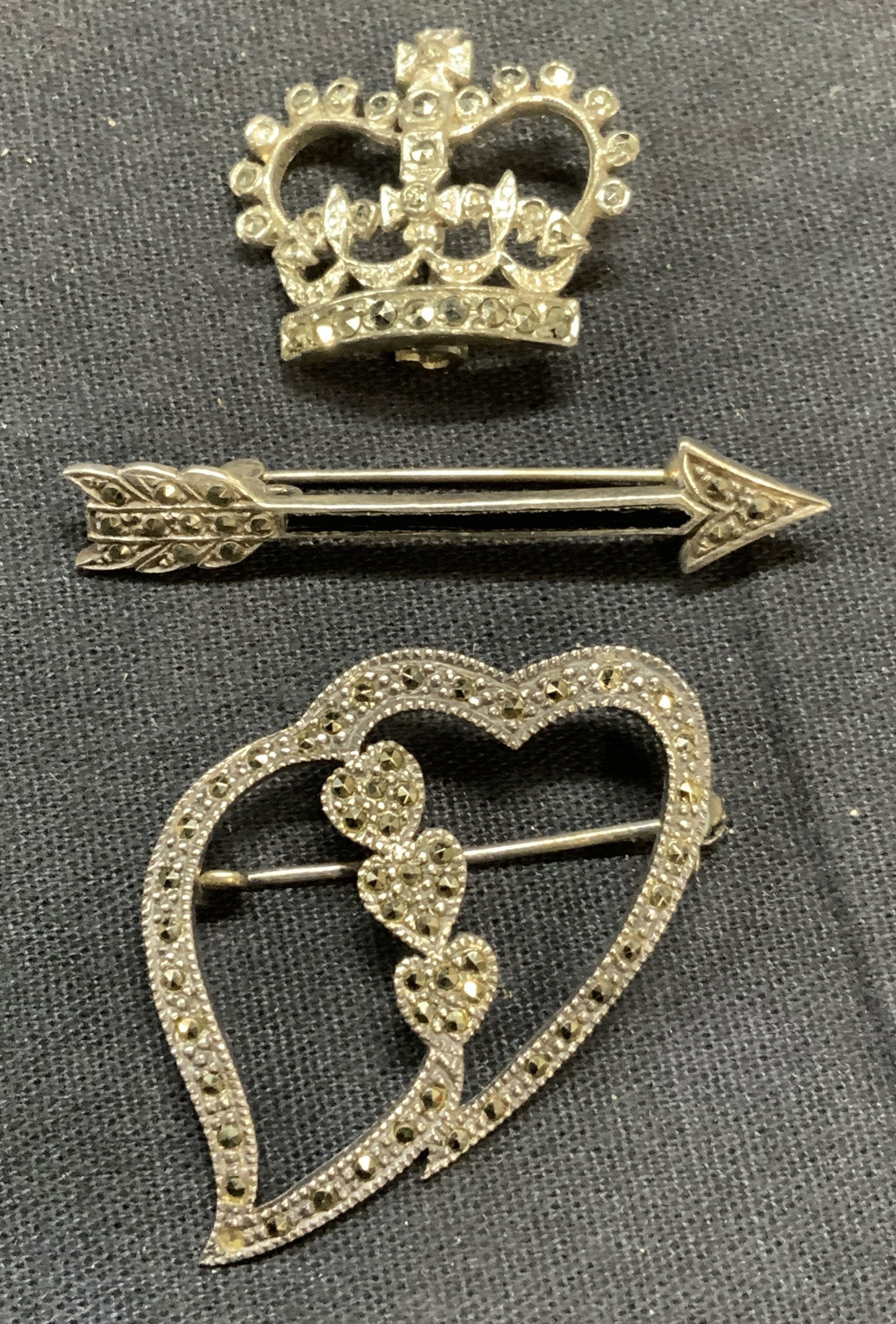 Lot 3 Sterling Silver Marcasite Brooches +: Lot of 3 jewelry pieces. 2 sterling silver and marcasite decorated brooches. Heart and arrow shapes. Arrow marked 925. Heart tests for sterling using PuriTEST kit. Largest piece measures approx. 1.75 