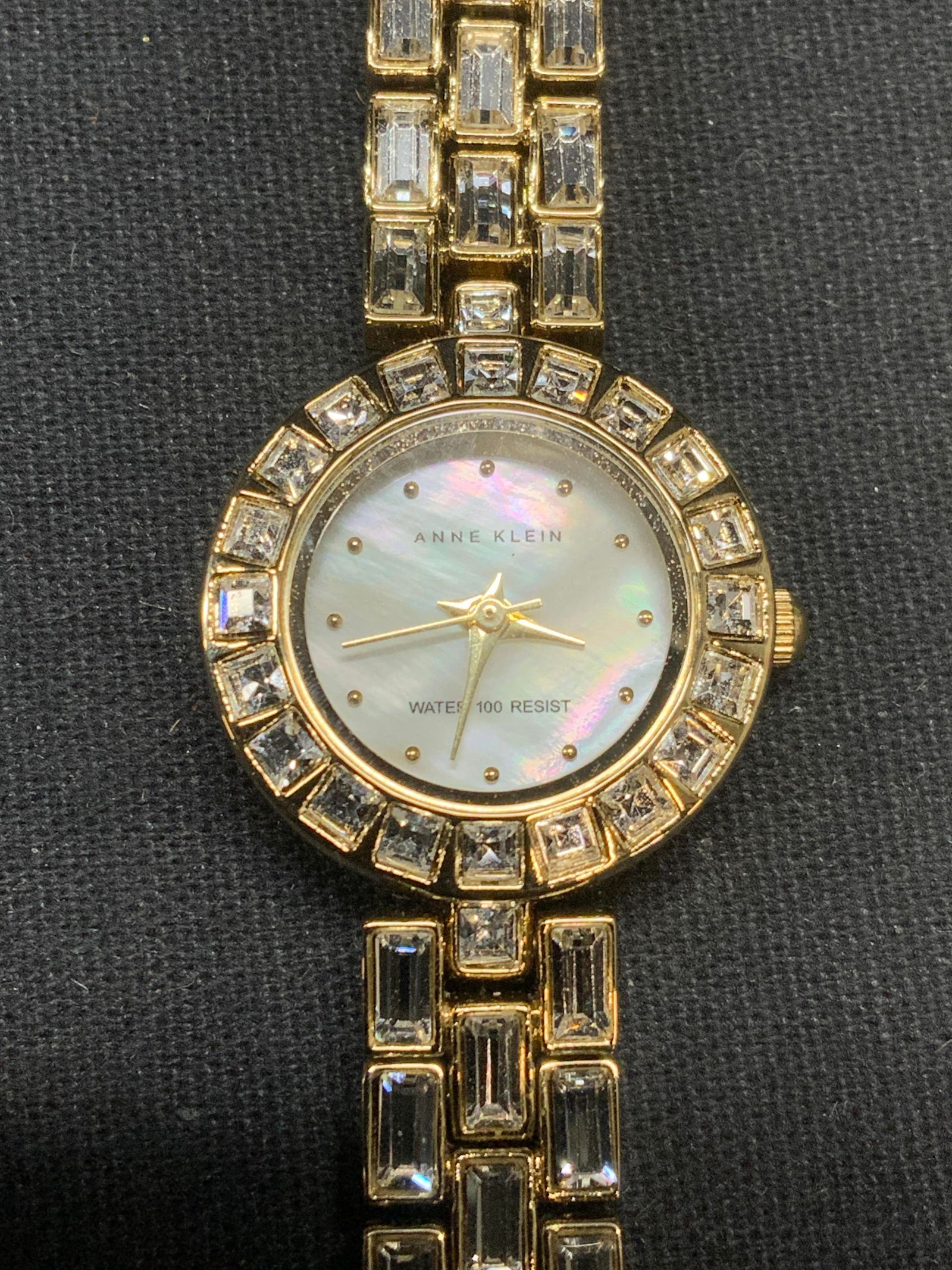 Vintage Anne Klein Gold Tone Crystal Watch: Vintage Anne Klein gold tone watch with chain strap and colorless crystal decoration. Signed on watch face. Stainless steel back. Measures approx. 6.75 inches long. Face measures approx. 1 inch wide.