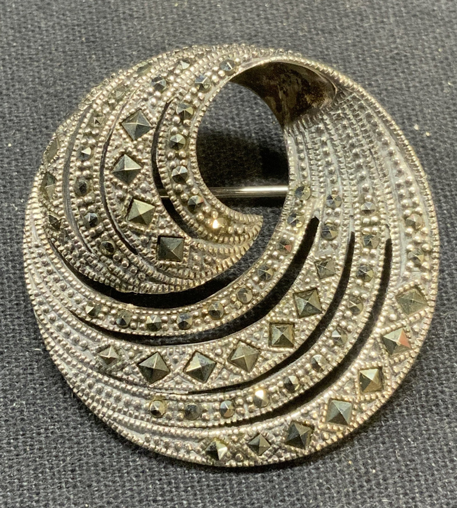 Vintage Sterling Silver Marcasite Swirl Brooch: Vintage sterling silver and marcasite decorated swirl brooch. Marked 925. Hinge pin to underside. Measures approx. 1.25 inches wide. Total weight 11.5 grams. Some scratching observed. Estate jewelry, 