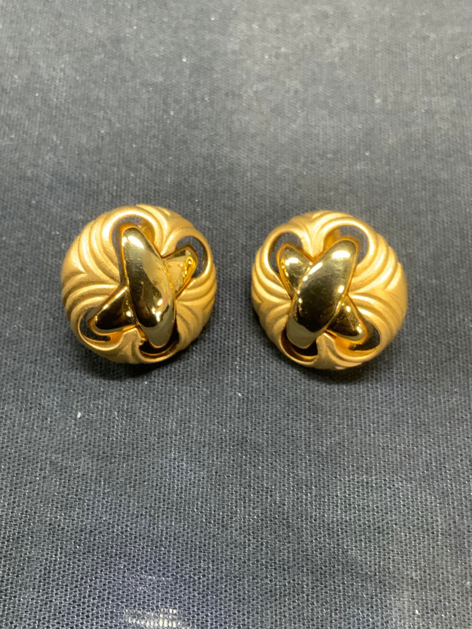 Vintage Judith Leiber Gold Tone X Earrings: Vintage Judith Leiber gold tone clip on earrings with sculptural X and embossed decoration. Signed to backing. Measure approx. 1 inch diameter. Some surface wear including scratching observed. Estate