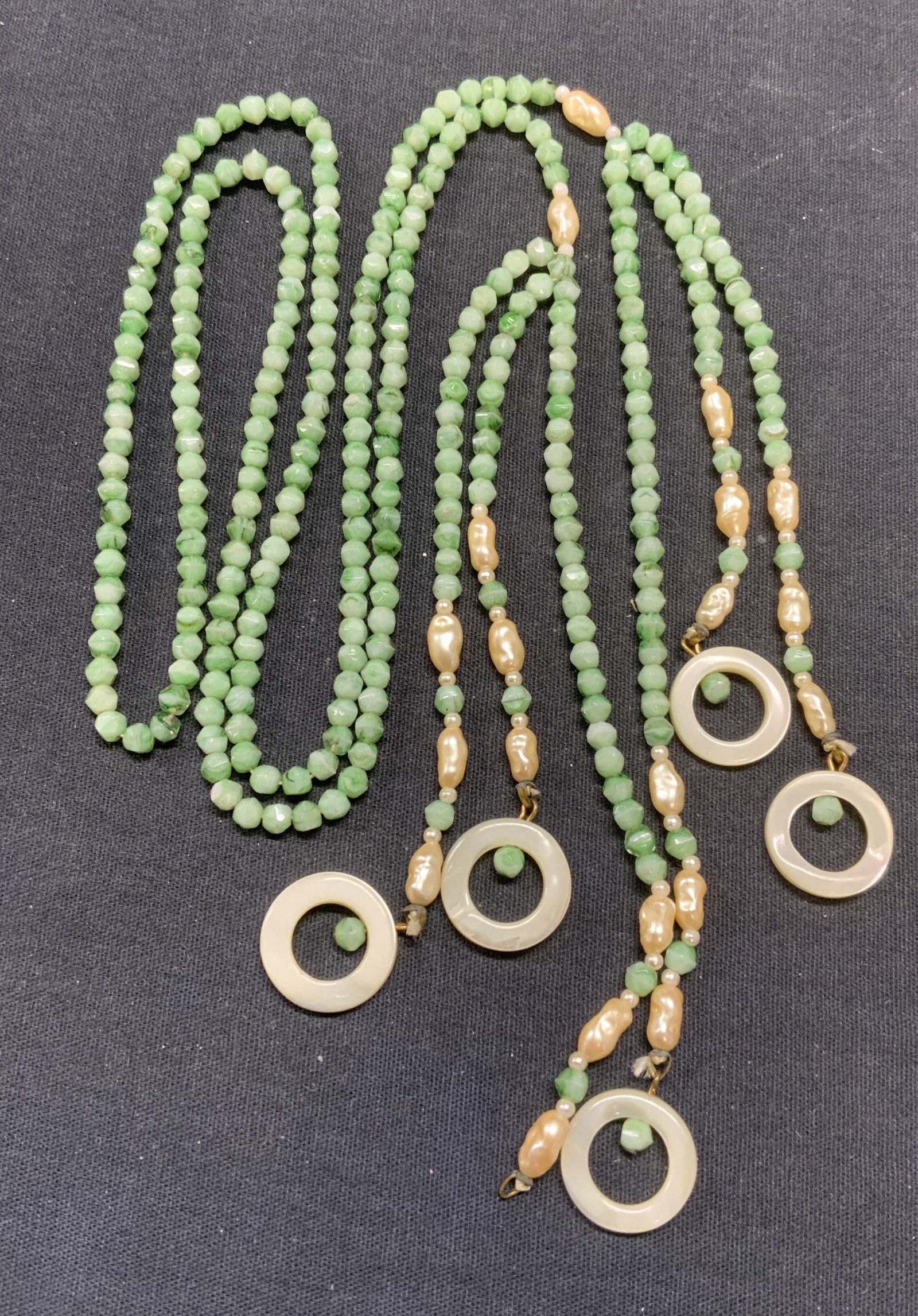 Mother of Pearl Green Crystal Lariat Necklace: Green crystal beaded lariat necklace with faux pearl and mother of pearl decorated tassels. Drop length approx. 15 inches. Tassel length approx 6.75 inches. Some surface wear including scratching obse