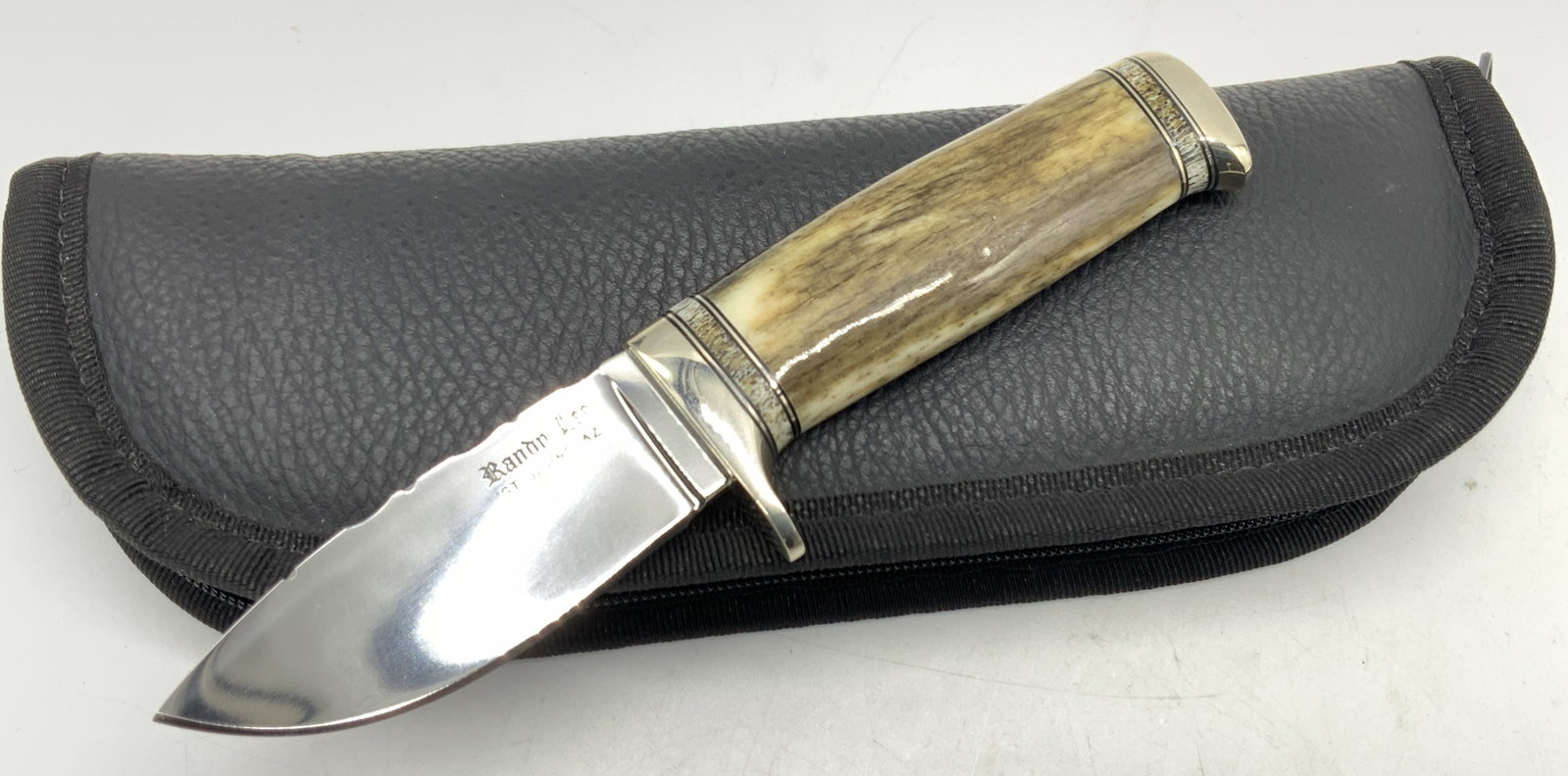 Randy Lee Antler & Steel Knife W Case: Marked on blade Randy Lee, St Johns Arizona. A knife of 7 inches long with a handle made of an antler or bone with steel pommel. Blade is approx 3 inches long and 1 inch wide, handle is approx 3.25 in