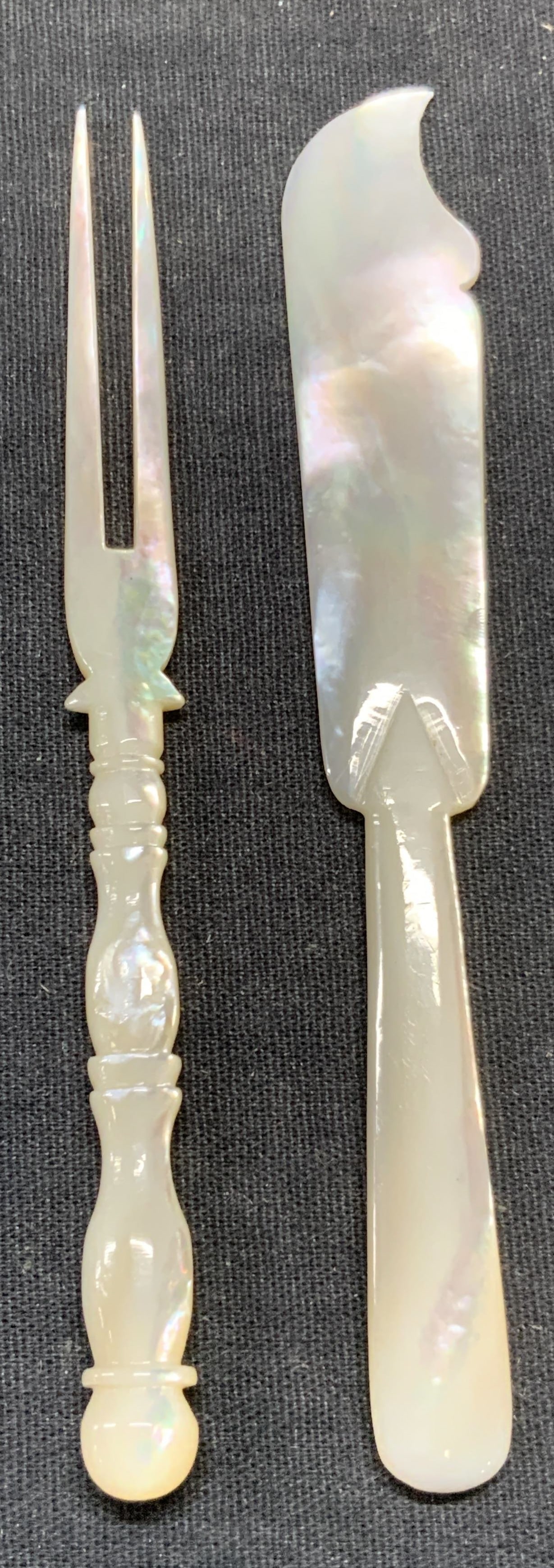 Lot 2 Vintage Mother of Pearl Knife & Fork: Vintage mother of Pearl and cocktail fork. Hand carved. Knife measures approx. 4.75 inches long. Fork measures approx. 4.75 inches long. Both pieces have some surface wear including scratching observe