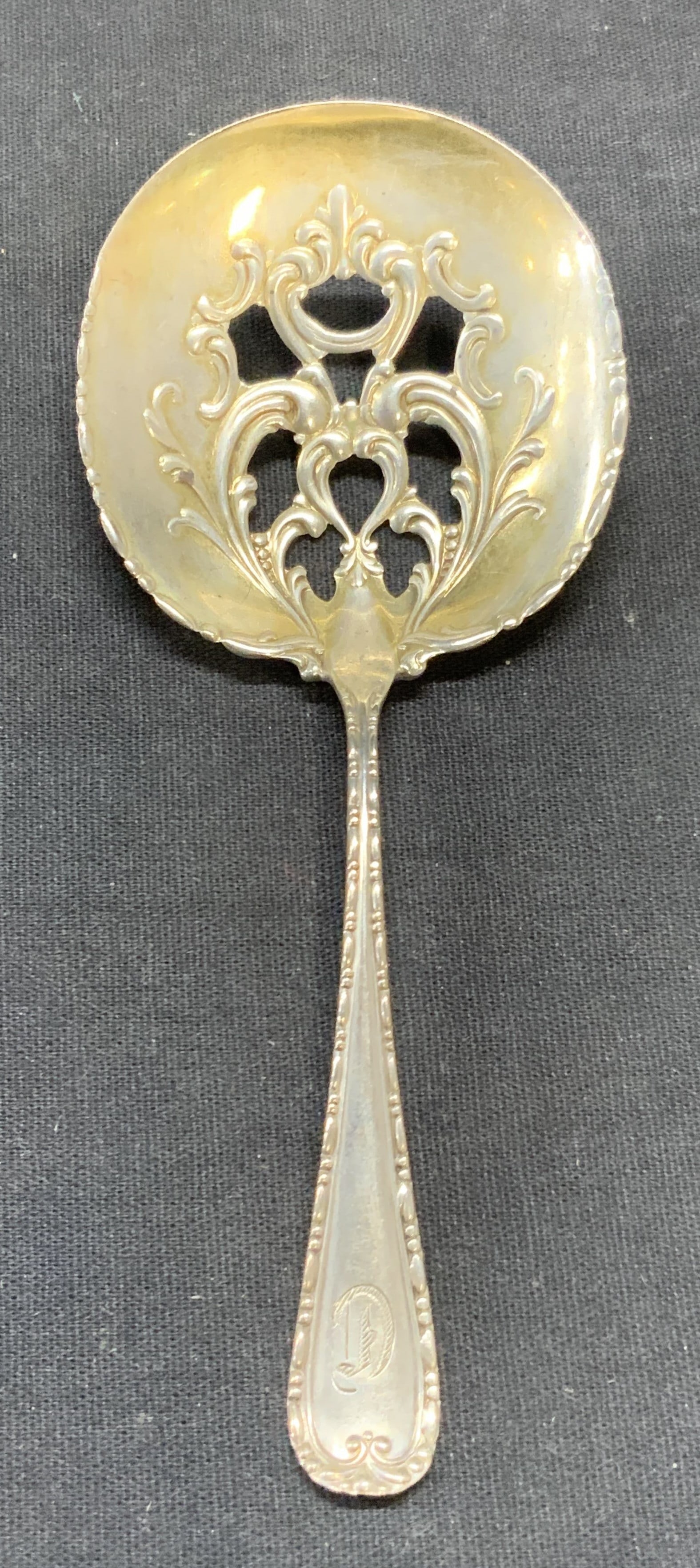 Antique CS Ball Sterling Silver Bon Bon Spoon: Antique C. S. Ball sterling silver Bon Bon spoon. Raised scroll motif and pierced spoon detail. Trademarked to underside. Marked sterling. Etched monogram on handle and etched date 1900 to underside. 