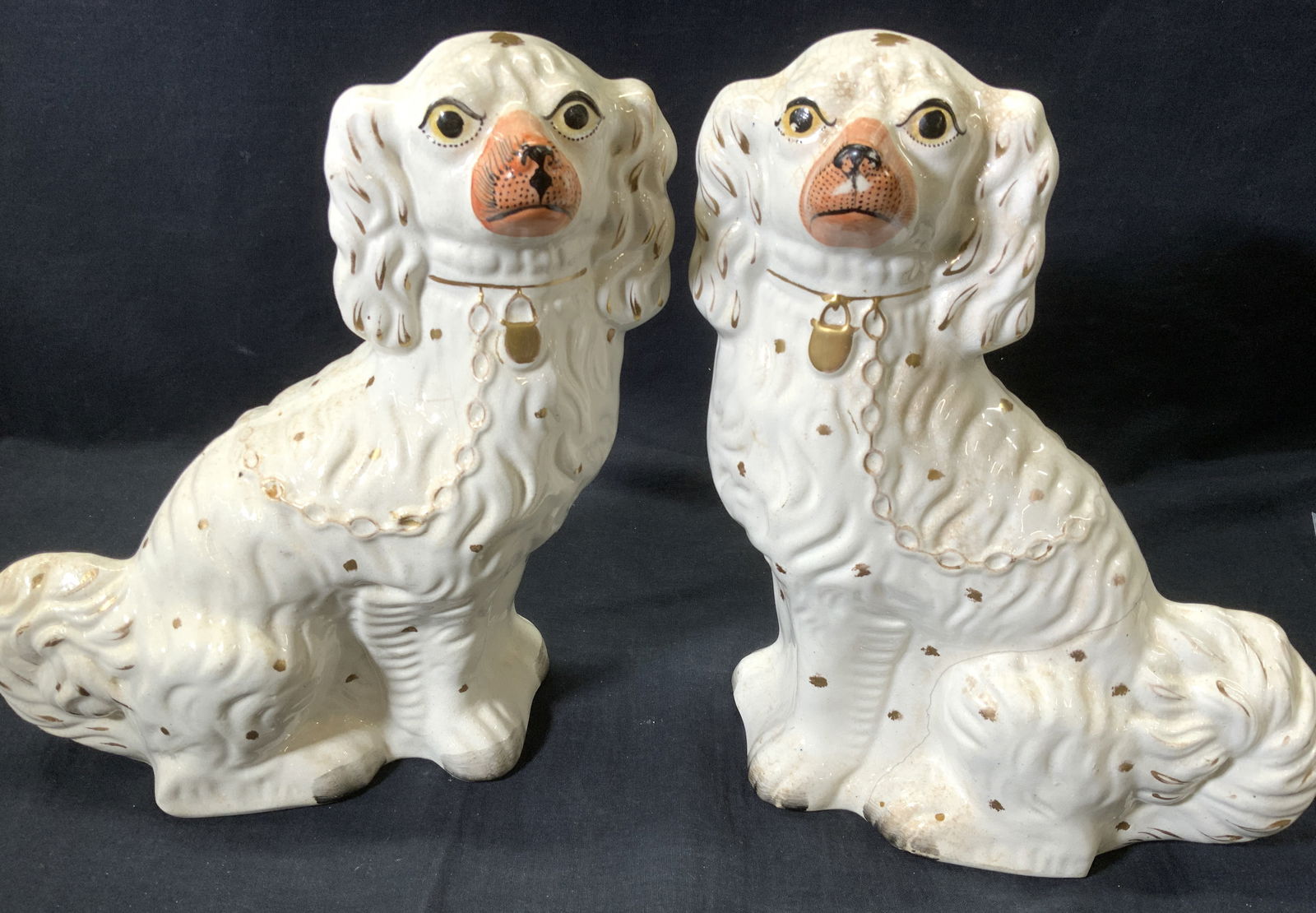 19th Cent Staffordshire Porcelain Spaniel Dogs, 2: Antique Staffordshire England Porcelain Spaniel Dog Statues with orange noses, yellow eyes, and gilt collar and chain. c. 1860s. Each measures 12.75 in. Ht x 9.25 in. Long x 5 in. Wide. Hand painted.