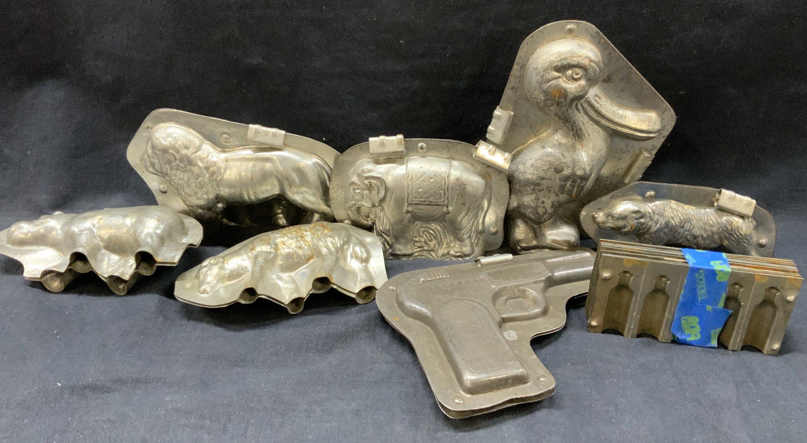 Lot 12 Vtg Aluminum Chocolate Molds: Lot of 12 vintage aluminum chocolate molds featuring animals such as lion. Bear, pelicans. Sheep and hippo along with 5 bottle molds and 1 pistol mold. Largest being approx 7 inches long. Evident wear