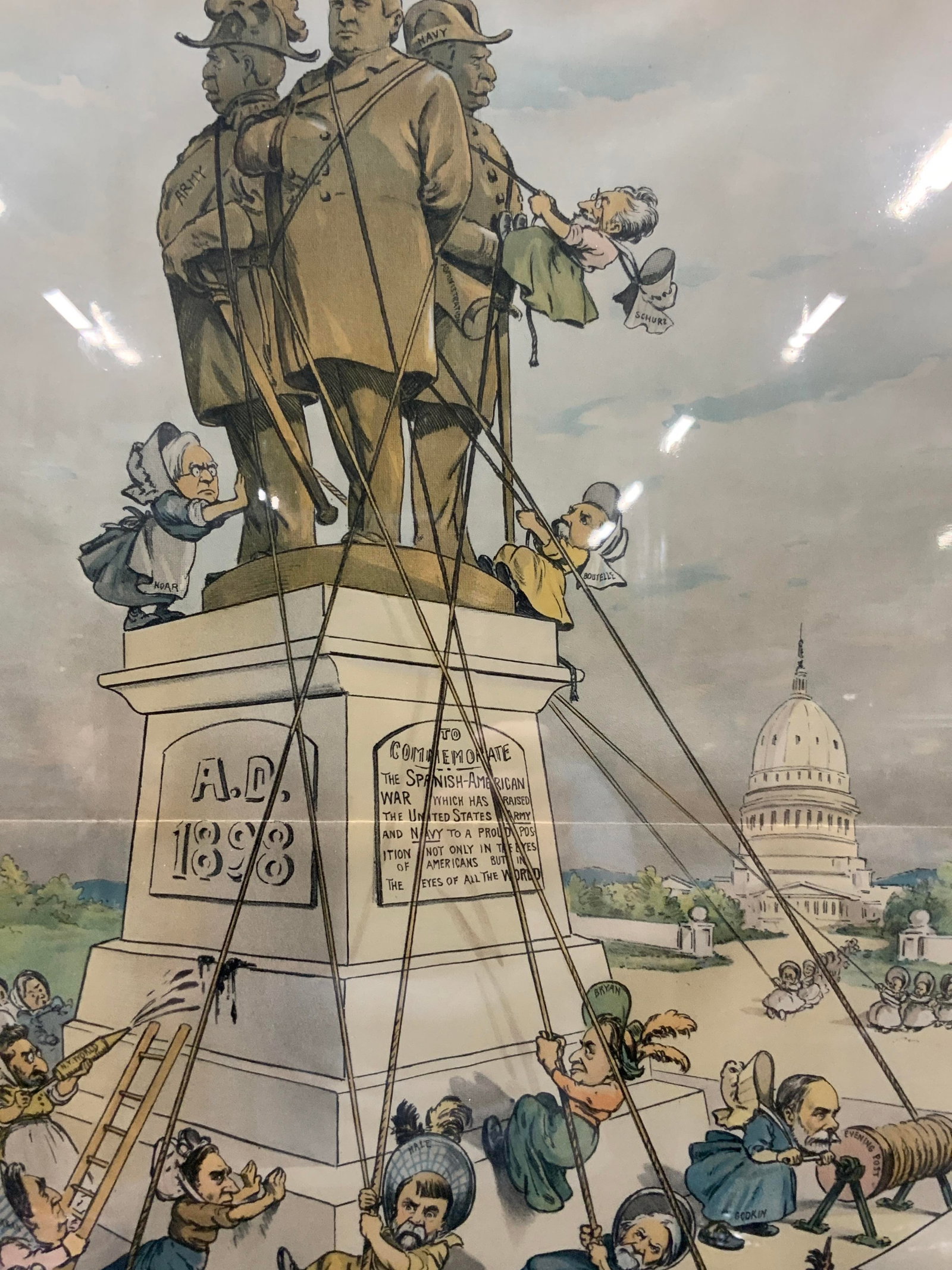 1899 Antq Puck Magazine Political Cartoon: Copyright 1899. Reads Our busy old women. Depicts various politicians dressed as older women, trying to pull down a statue from the Spanish American war, that raised the United States Army and navy to