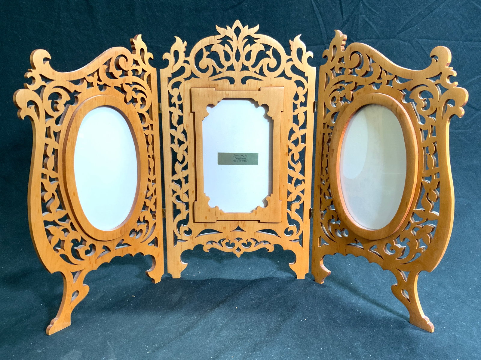 Fretwork Carved Wood Folding Triple Picture Frame: Picture frame is tan toned and wooden. Piece has intricately detailed fretwork. Frame has 3 windows. Picture frame folds and has 6 feet. Picture frame measures approximately 21 inches wide when fully